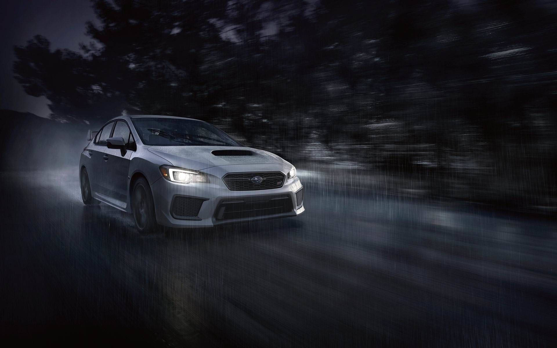 Subaru 桌布 壁紙 — 一輛銀色Subaru WRX在夜間穿過被雨水浸濕的森林，車頭燈劃破迷霧。