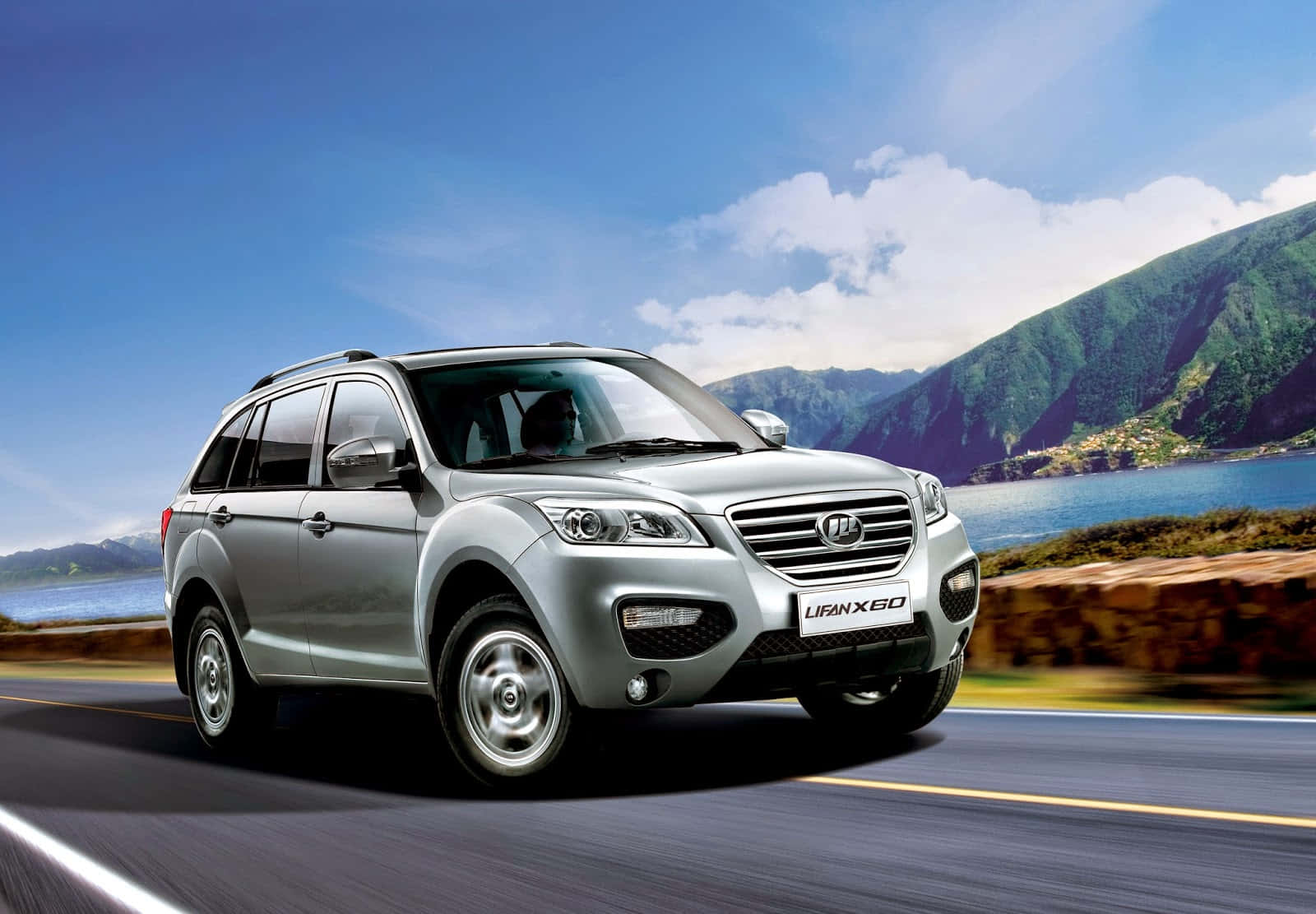 Lifan 桌布 壁紙 — 一輛銀色力帆X60 SUV在明亮的藍天下沿著海岸公路行駛，背景是山脈和湖泊。