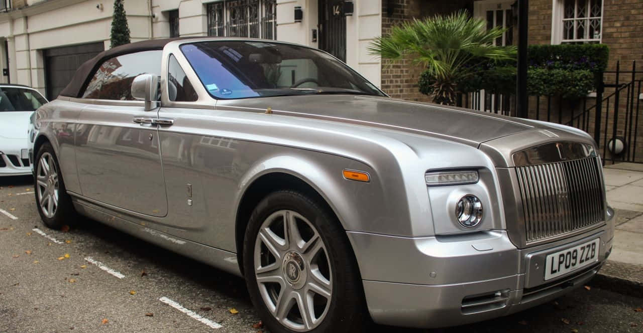 Rolls Royce Phantom Drophead Coupe 桌布 壁紙 — 一輛銀色勞斯萊斯 Phantom Drophead Coupe 停放在住宅街道上，人行道上散落著秋天的落葉。