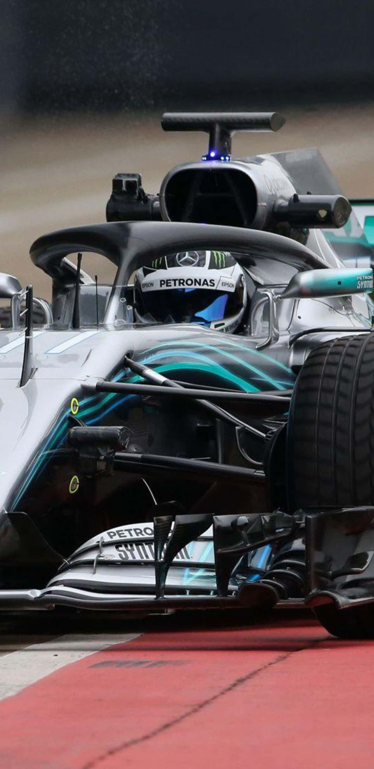 Formula 1 桌布 壁紙 — 一輛銀色和藍綠色的F1賽車在賽道上高速行駛的特寫鏡頭，帶有紅色路緣石和輪胎噴出的水花。