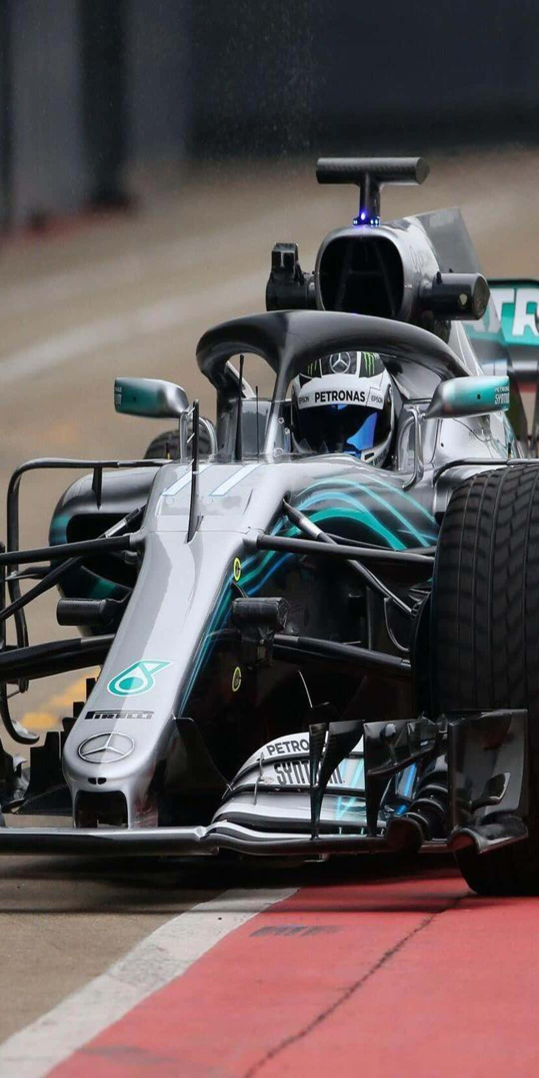 F1 桌布 壁紙 — 一輛銀色和青綠色的梅賽德斯一級方程式賽車，車手戴著頭盔，沿著紅白相間的賽道邊緣疾馳。