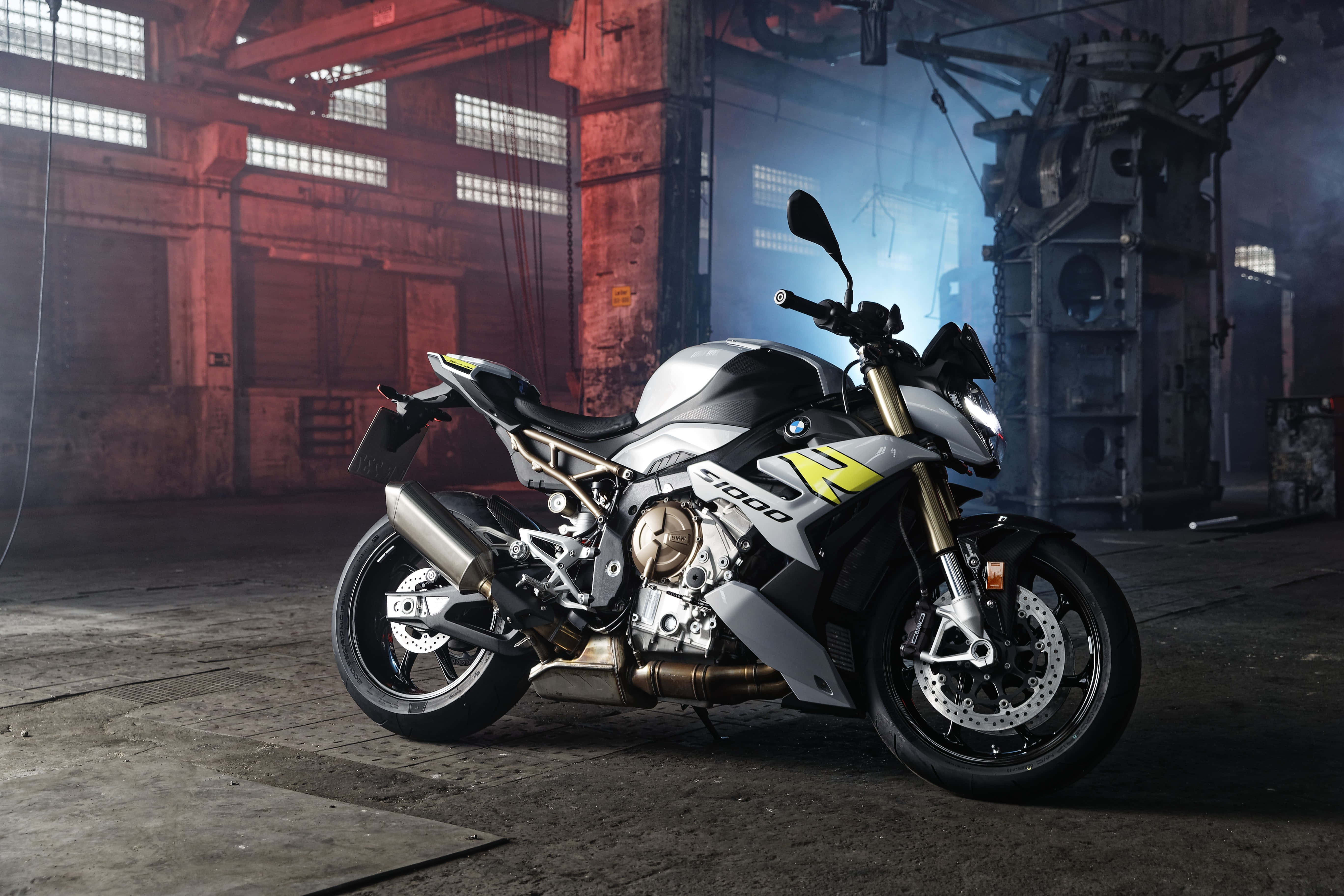 Superbike 桌布 壁紙 — 一輛銀色和黃色的BMW S1000R摩托車，在昏暗的工業倉庫中，紅磚牆和鋼樑襯托下，顯得格外時尚。