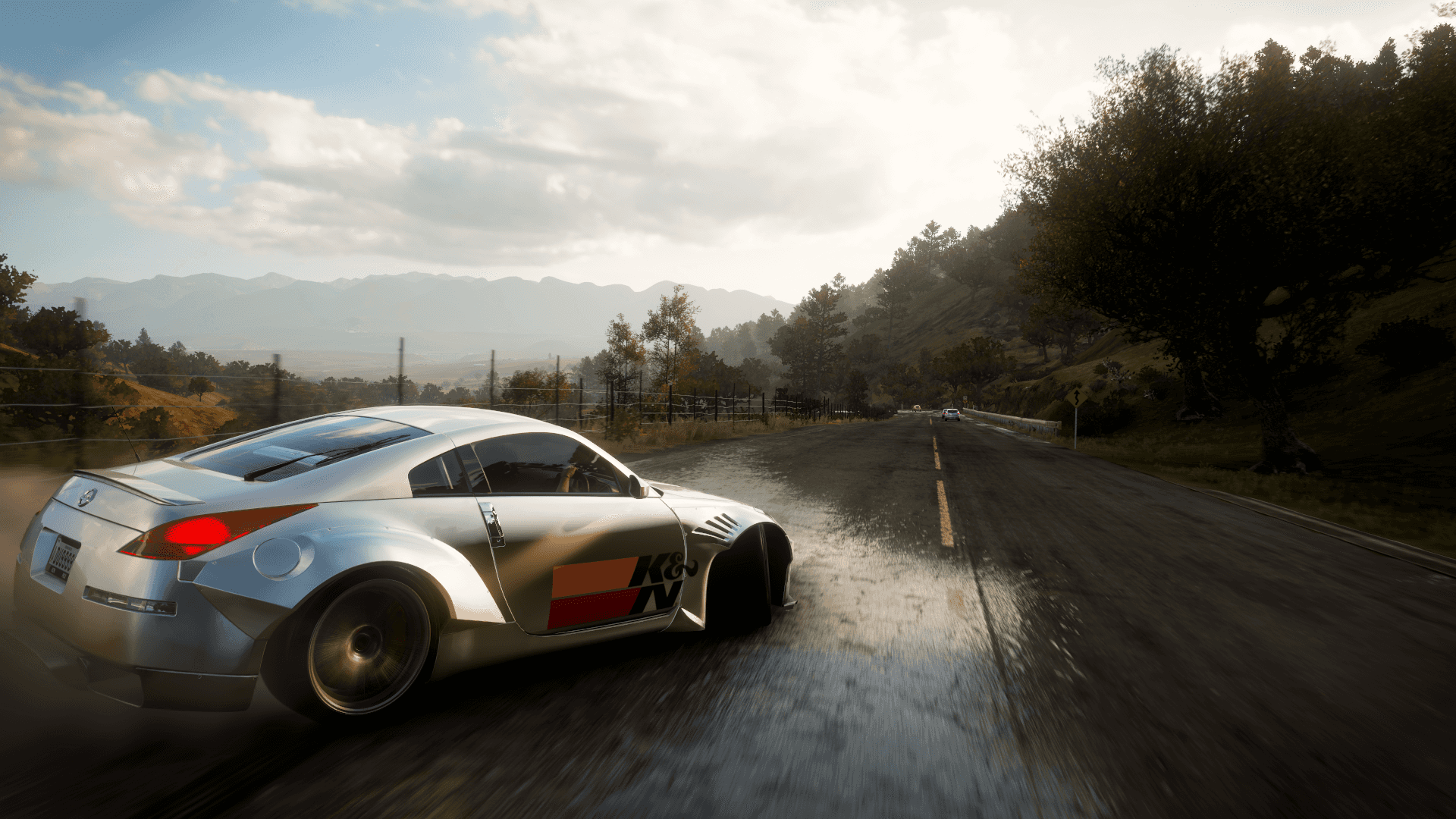 Forza 4 桌布 壁紙 — 一輛銀色日產350Z在潮濕的山路上飄移，周圍有樹木和遠處的山峰，天空多雲。