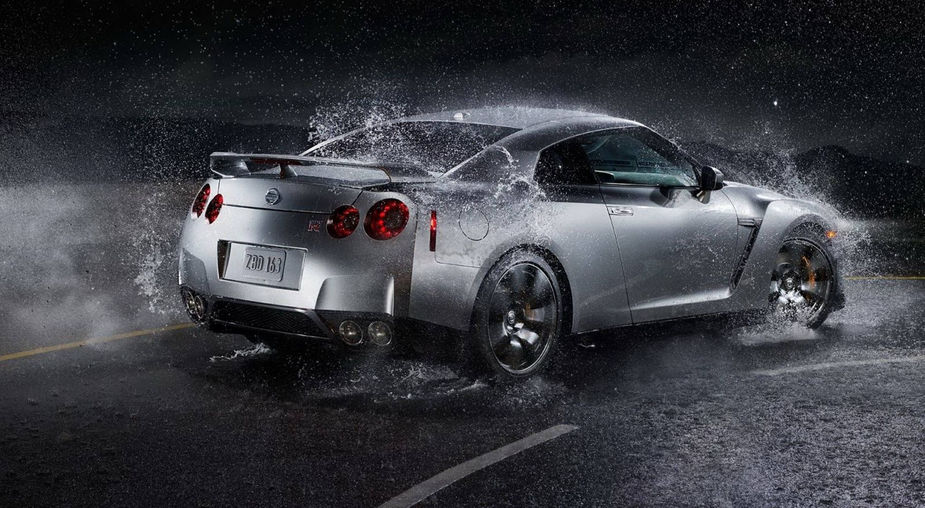 Nissan 桌布 壁紙 — 一輛銀色日產GT-R在濕滑的雨夜路面上飛馳，激起的水花在夜空中飛濺。