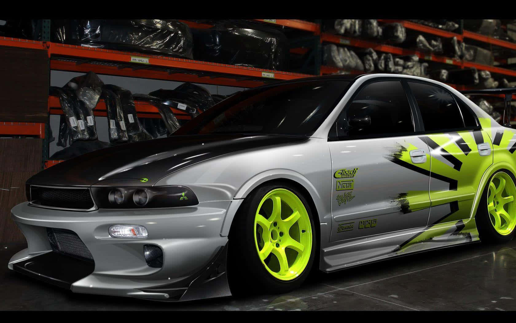 Modified Car 桌布 壁紙 — 一輛銀色日產Skyline，配備螢光綠色車輪和醒目的黑綠色圖案，停放在設有橙色貨架的倉庫中。