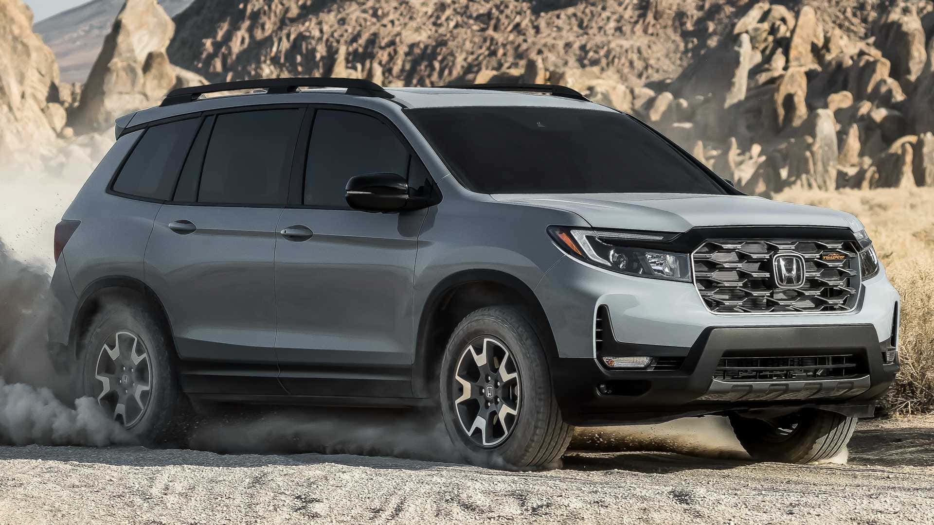 Honda Passport 桌布 壁紙 — 一輛銀色本田 Pilot SUV 在崎嶇多石的沙漠地形上行駛，揚起灰塵。
