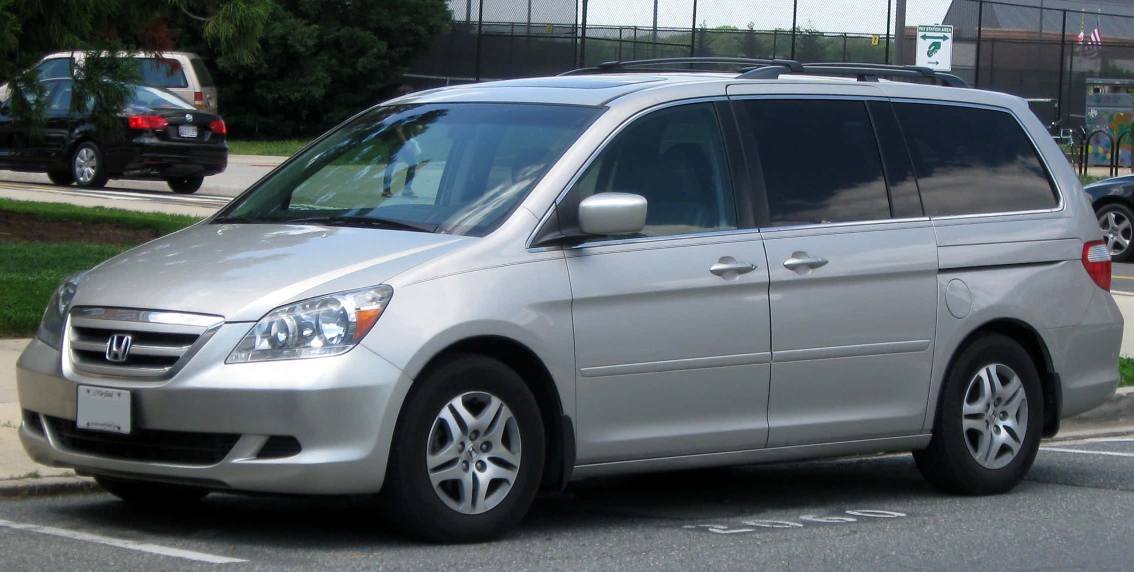 Honda Odyssey 桌布 壁紙 — 一輛銀色本田Odyssey小型貨車停放在一個有樹木和圍欄的停車場中。