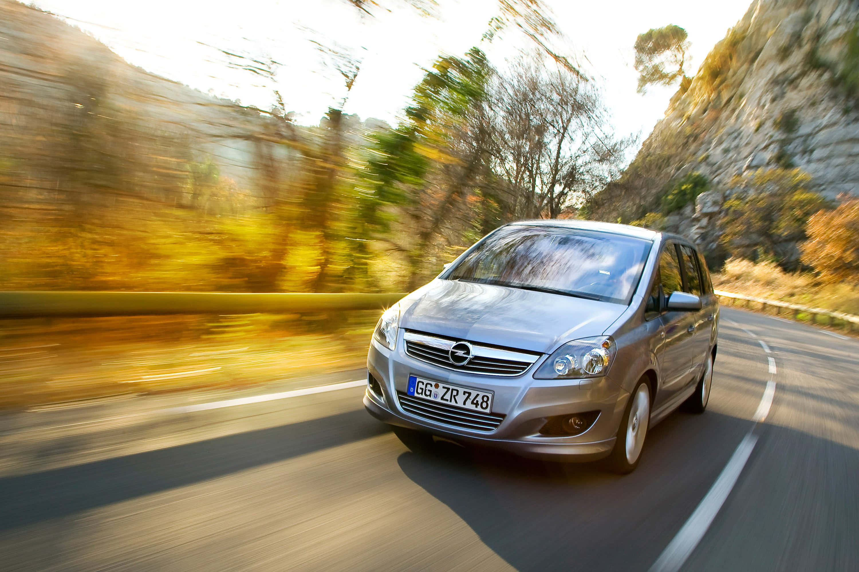 Opel Zafira 桌布 壁紙 — 一輛銀色歐寶Zafira在蜿蜒的山路上疾馳，金色的秋葉模糊掠過。
