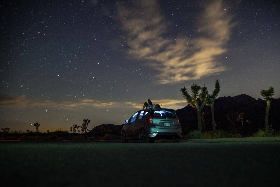 Beautiful Night 桌布 壁紙 — 一輛銀色汽車停泊在繁星點點的沙漠夜空下，車頂上坐著兩個人，附近有約書亞樹。