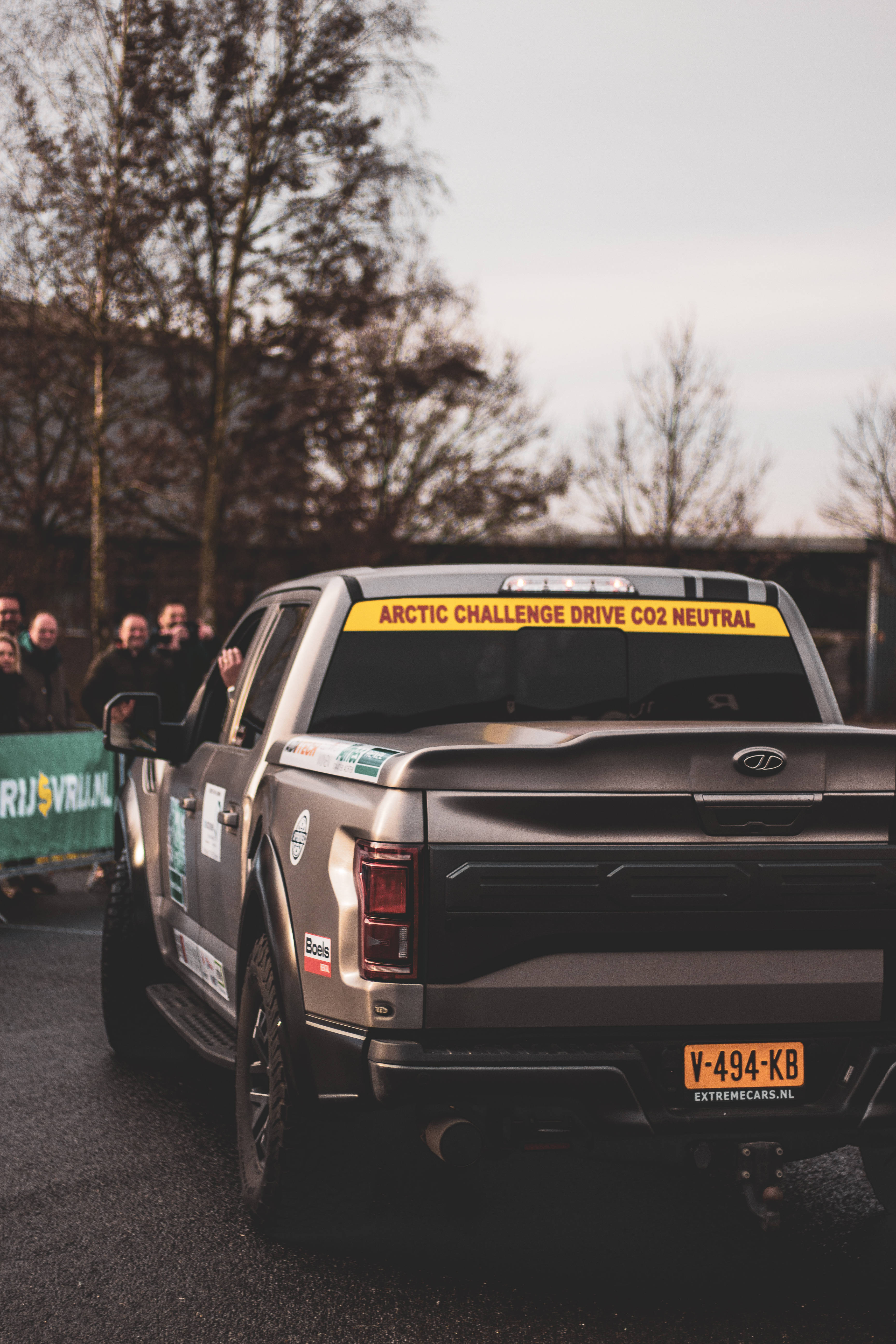 Raptor 桌布 壁紙 — 一輛銀色皮卡車帶有'Arctic Challenge Drive CO2 Neutral'貼紙，在黃昏時駛過觀眾。