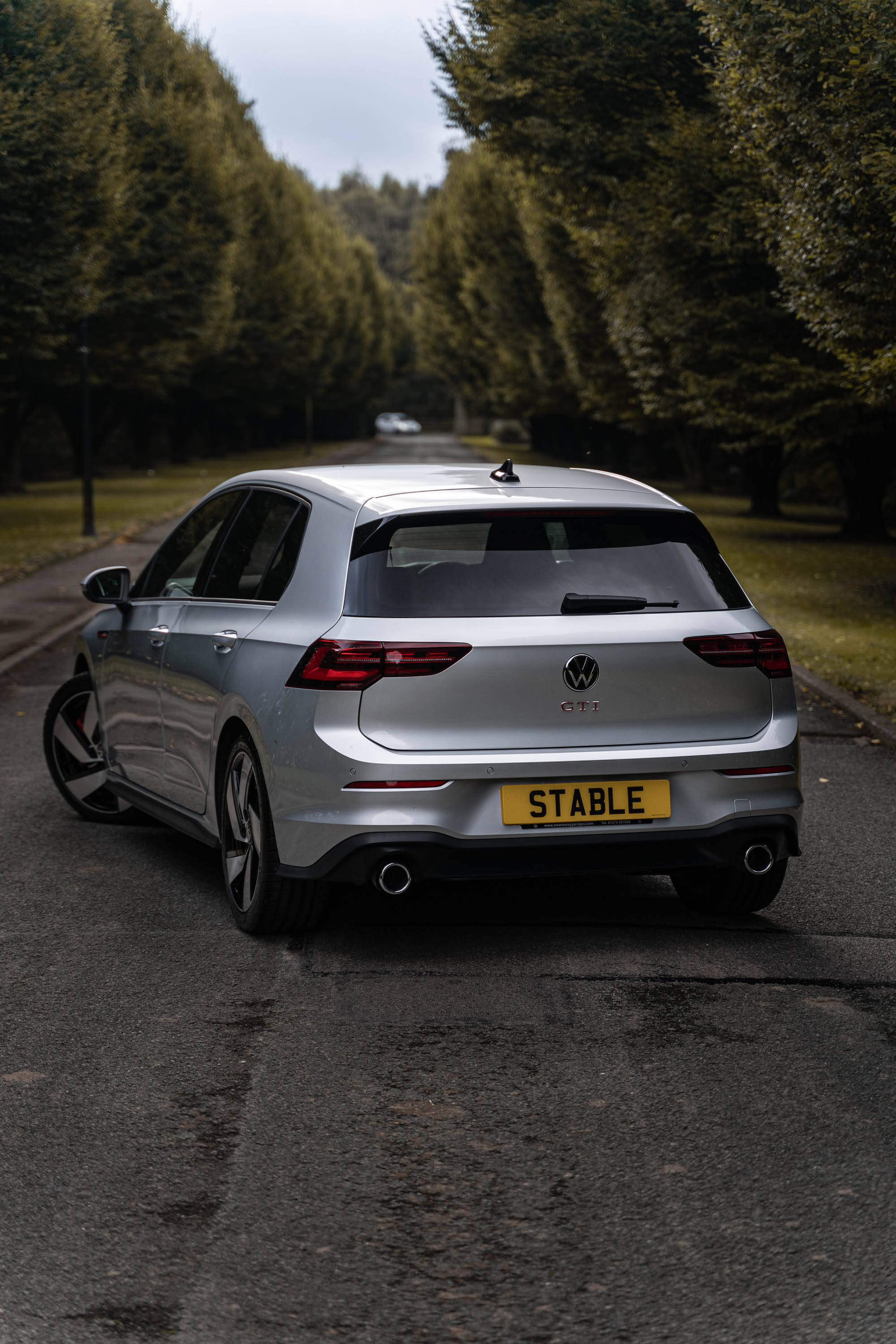 Gti 桌布 壁紙 — 一輛銀色福斯 Golf GTI 停放在潮濕的樹蔭道路上，天空多雲。