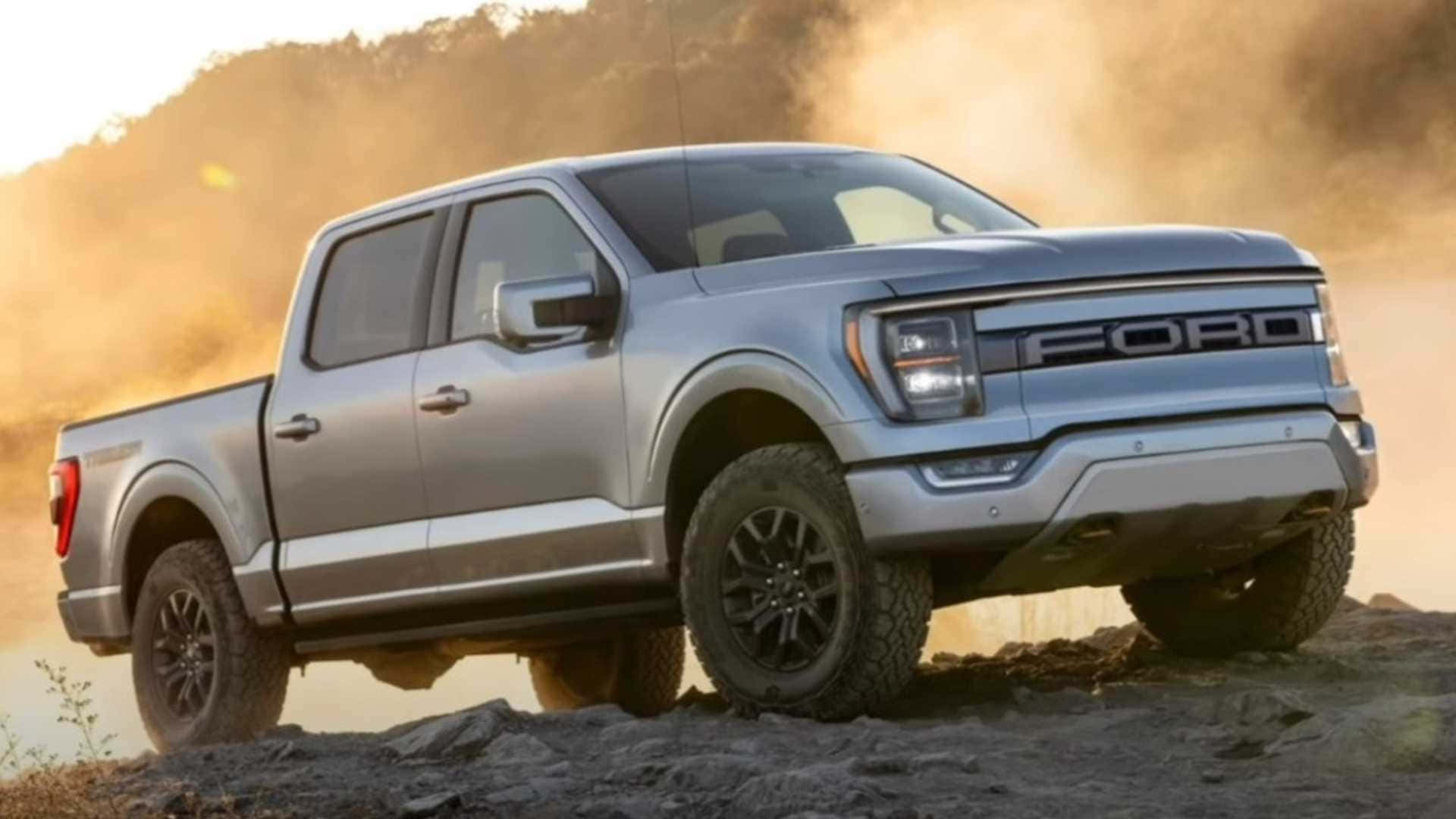 Ford Truck 桌布 壁紙 — 一輛銀色福特F-150皮卡車在塵土飛揚的地形中強勁行駛，堅固的輪胎揚起泥土，背景是金色的日落。