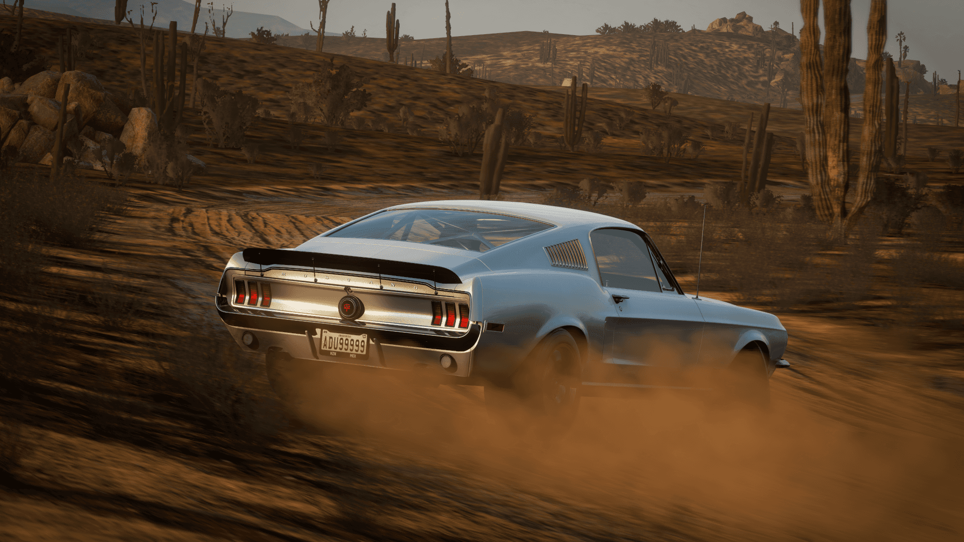 mustang HD 桌布 壁紙 — 一輛銀色經典肌肉車在烈日曝曬、長滿高大仙人掌的沙漠中疾馳，揚起塵土。