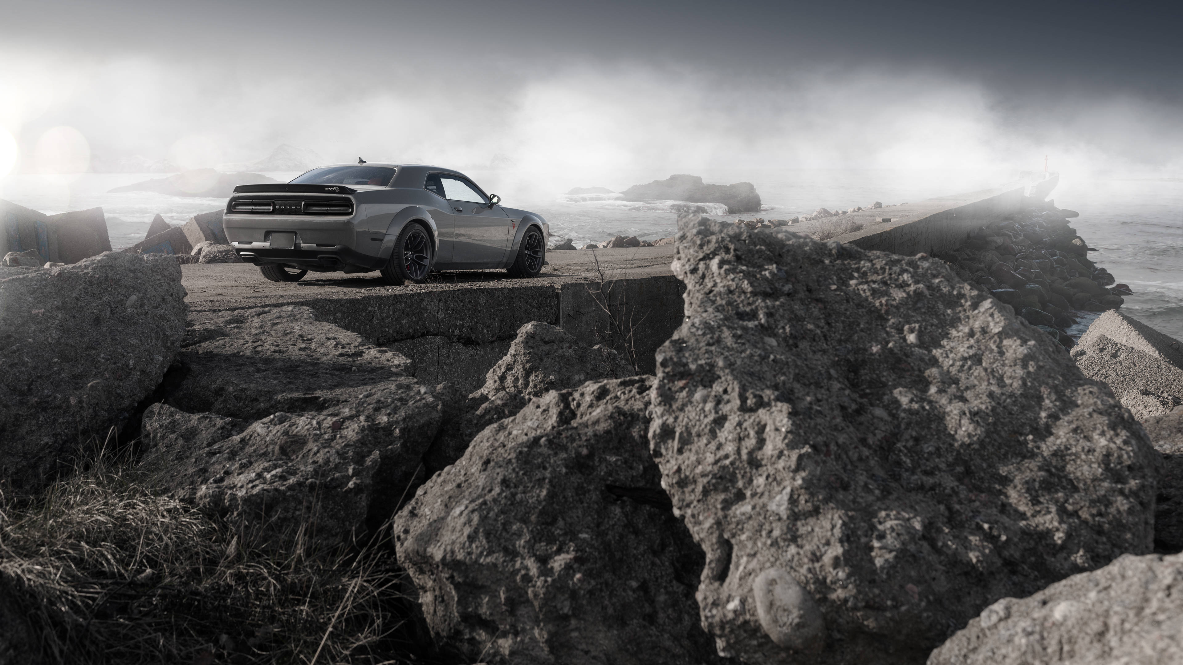 Dodge 桌布 壁紙 — 一輛銀色肌肉車停在崎嶇的海岸岩石上，霧氣瀰漫的海浪在暴風雨的天空下拍打著下方。