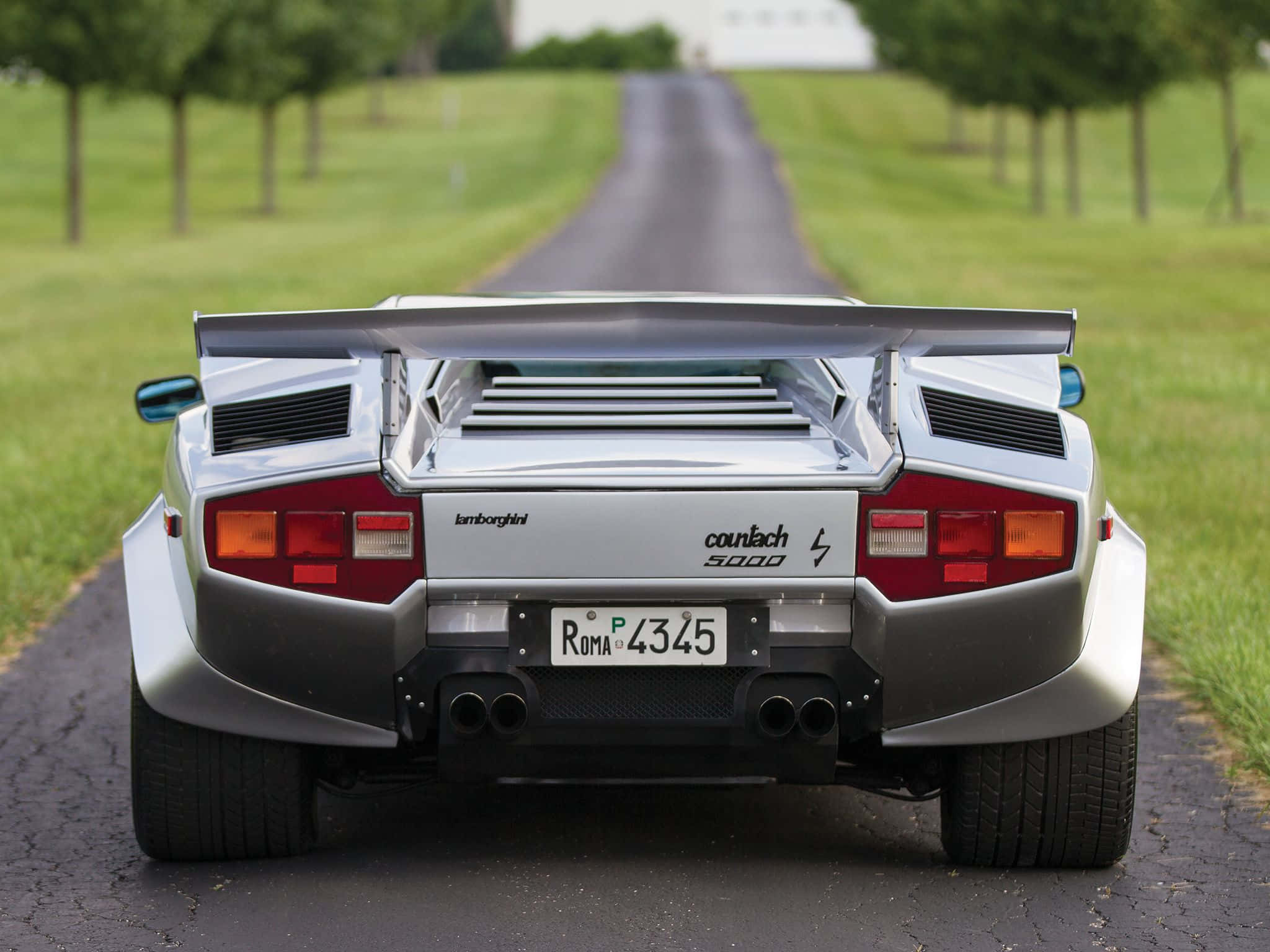Lamborghini Countach 桌布 壁紙 — 一輛銀色藍寶堅尼Countach 5000停放在兩側有草地田野的林蔭道路上。