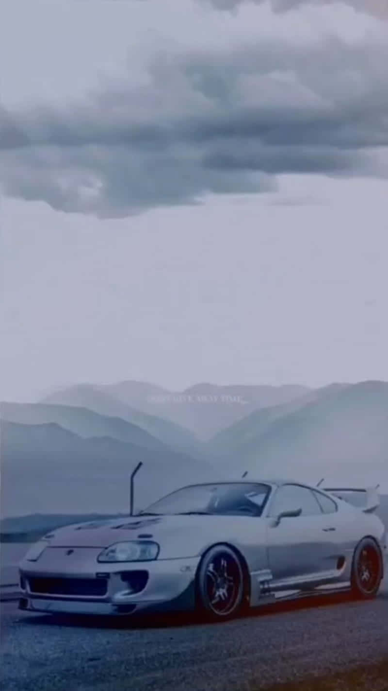 桌布 壁紙 — 一輛銀色豐田Supra跑車停泊在道路上，背景是霧濛濛的山脈和陰天。
