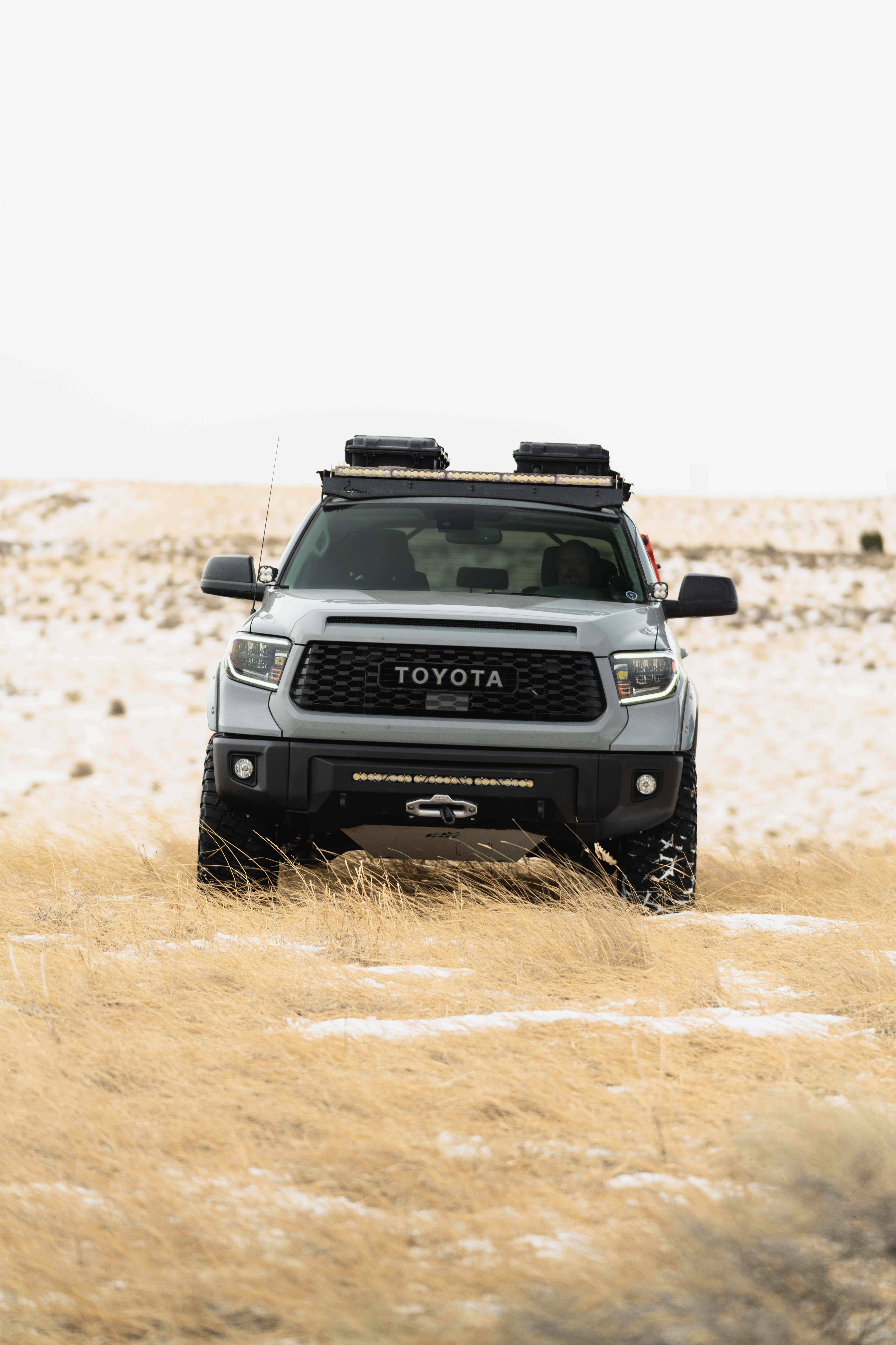 Toyota 桌布 壁紙 — 一輛銀色豐田Tacoma配備車頂架，在陰天下的雪地乾草田中矗立。