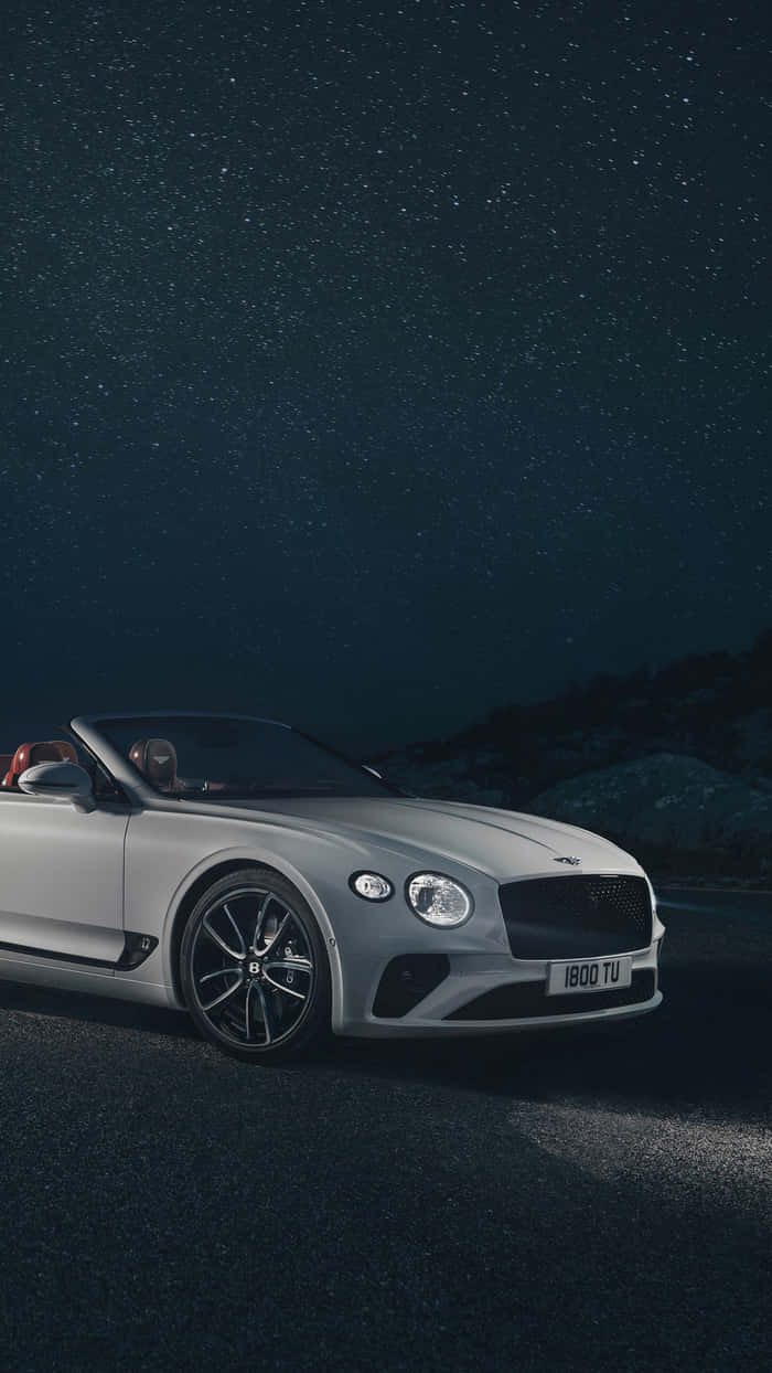 Bentley Continental Gt 桌布 壁紙 — 一輛銀色賓利敞篷車停泊在星空下，車內有兩個人。