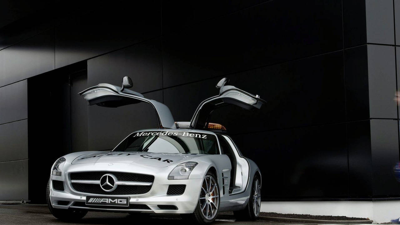 Mercedes 桌布 壁紙 — 一輛銀色賓士 SLS AMG 安全車，鷗翼車門打開，停在一座時尚的黑色建築前。