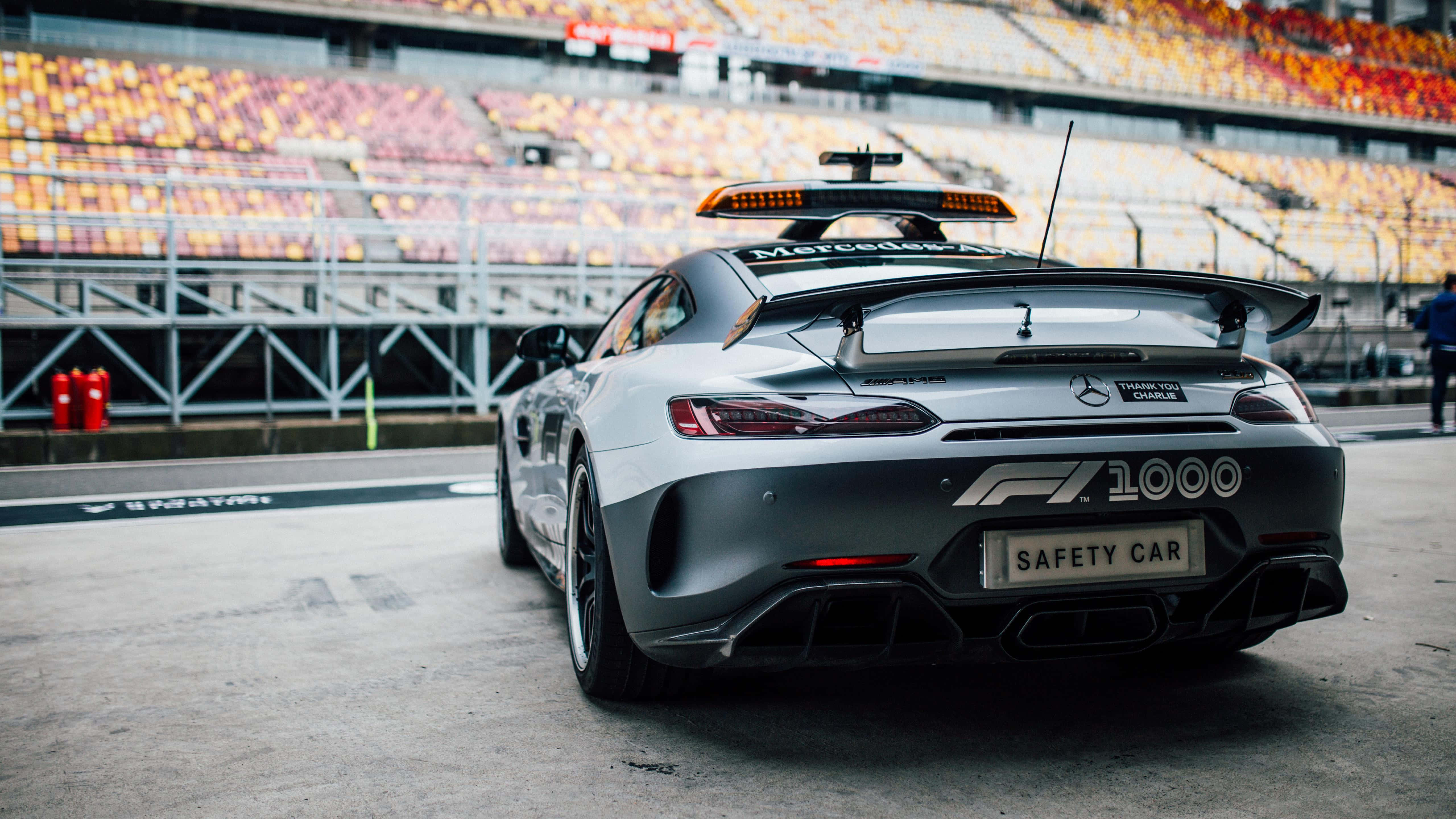 Safety Car 桌布 壁紙 — 一輛銀色賓士AMG GT R安全車，帶有「F1 1000」和「SAFETY CAR」貼紙，停在賽道上，背景是空無一人的看台。
