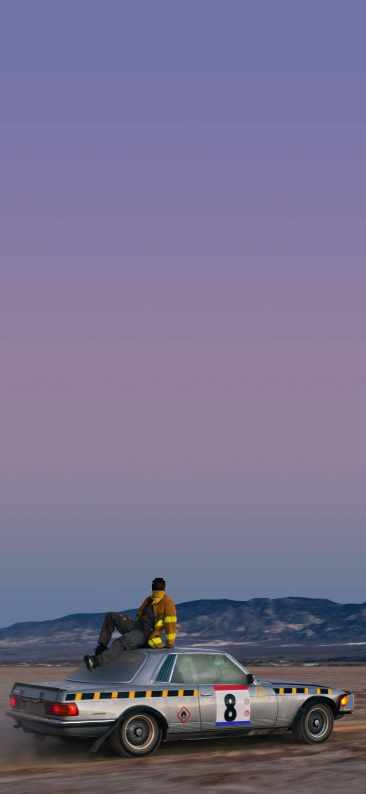Purple Sky 桌布 壁紙 — 一輛銀色賽車，號碼8，在黃昏時分疾馳穿過沙漠，車頂上坐著一個人，背景是紫色的山脈。