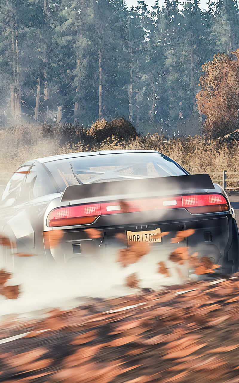 Android Forza Horizon 4 桌布 壁紙 — 一輛銀色跑車在森林道路上疾馳，揚起秋葉和灰塵，形成動態模糊效果。