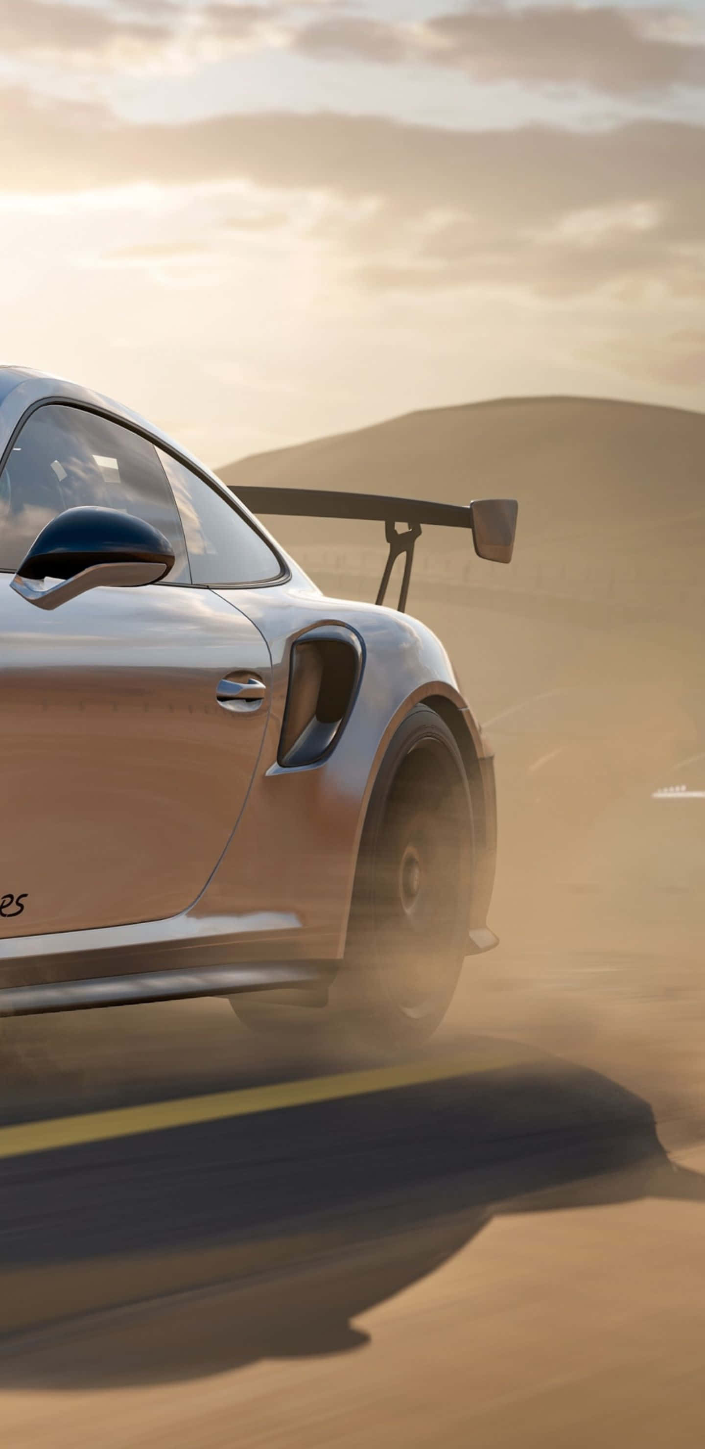 Pixel 3xl Forza Motorsport 7 桌布 壁紙 — 一輛銀色跑車帶有大型後擾流板，在金色夕陽天空下的沙漠公路上疾馳，揚起灰塵。