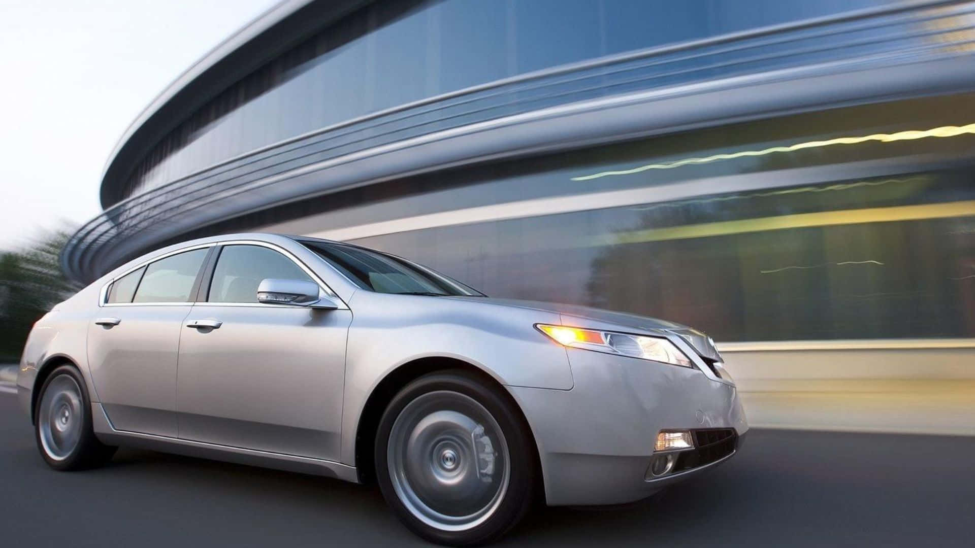 Acura Tl 桌布 壁紙 — 一輛銀色轎車高速駛過現代玻璃建築，動態模糊強調了速度。