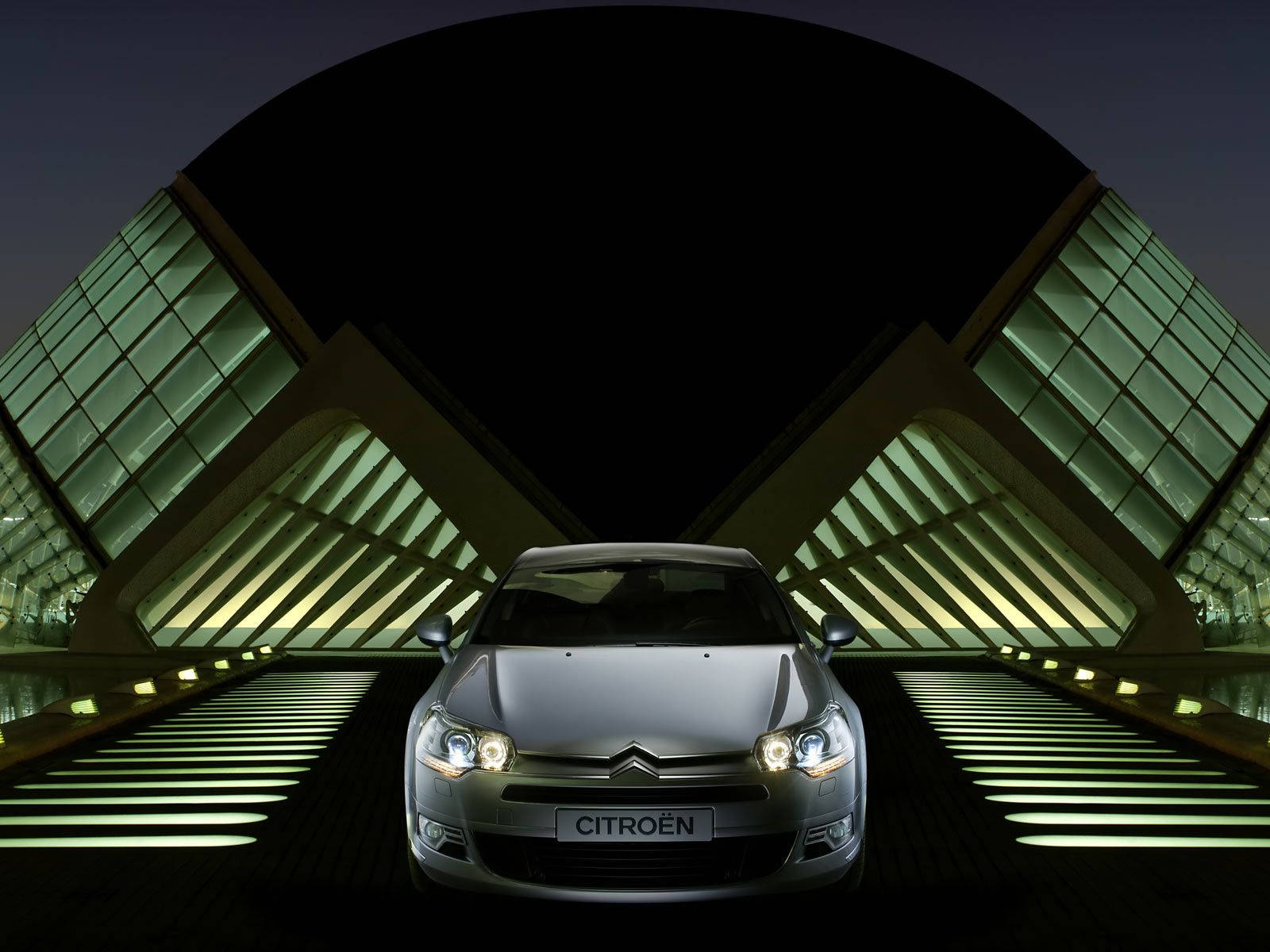 Citroen 桌布 壁紙 — 一輛銀色雪鐵龍汽車在夜間於未來風格的玻璃和鋼拱門下，在發光的綠色燈光下閃閃發光。