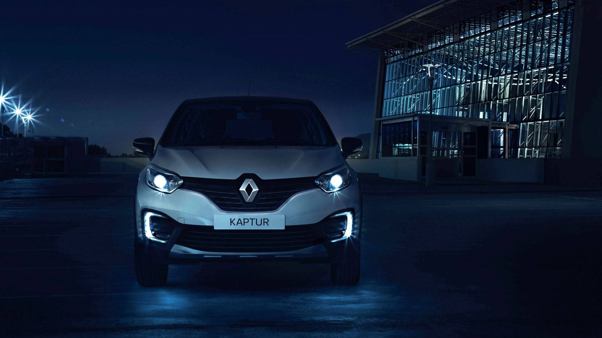 Renault 桌布 壁紙 — 一輛銀色雷諾Captur SUV在明亮的車頭燈下閃耀，背景是黑暗的城市夜景和玻璃建築。