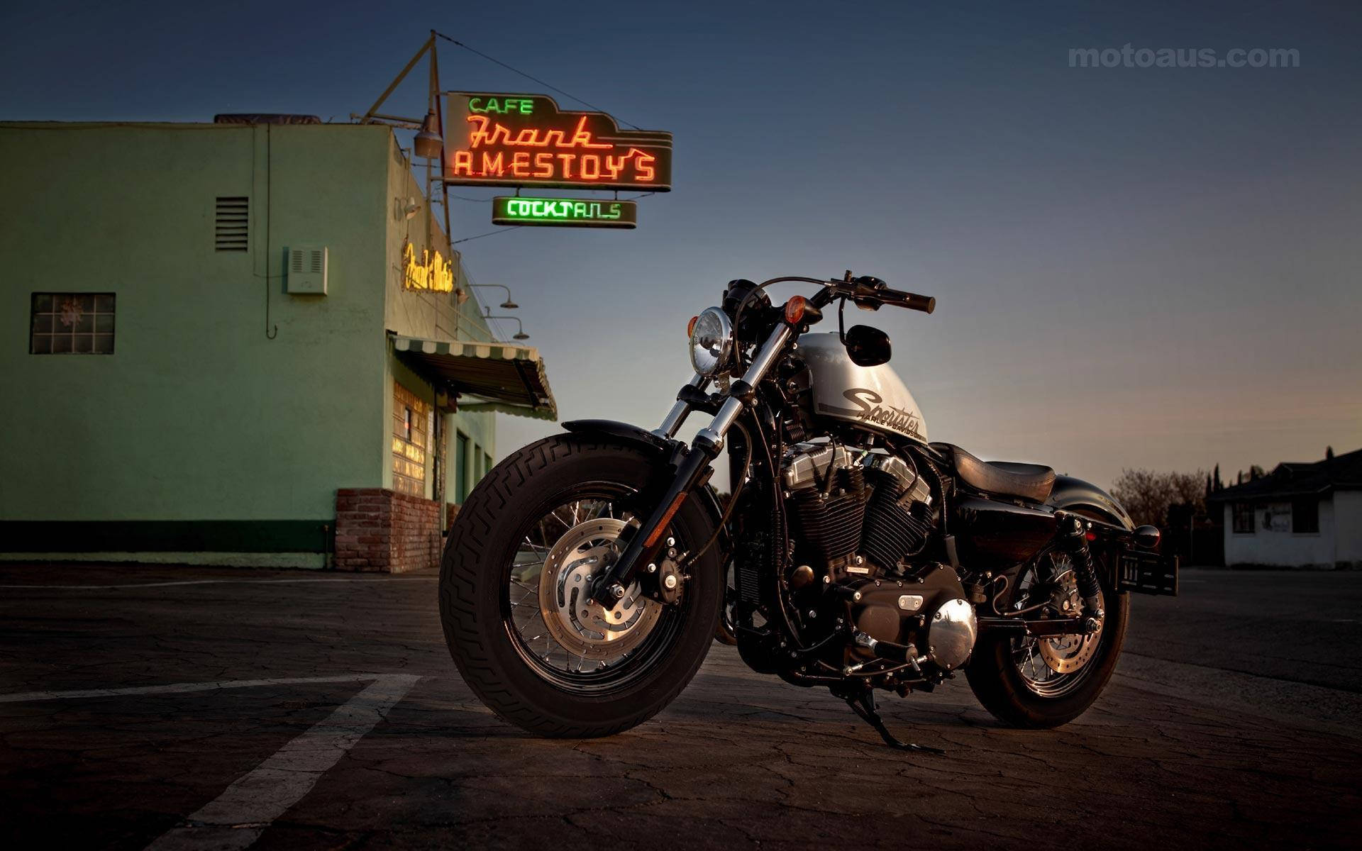 Harley 桌布 壁紙 — 一輛鍍鉻機車在黃昏時停在一間霓虹燈咖啡館前，周圍有溫暖的環境照明。