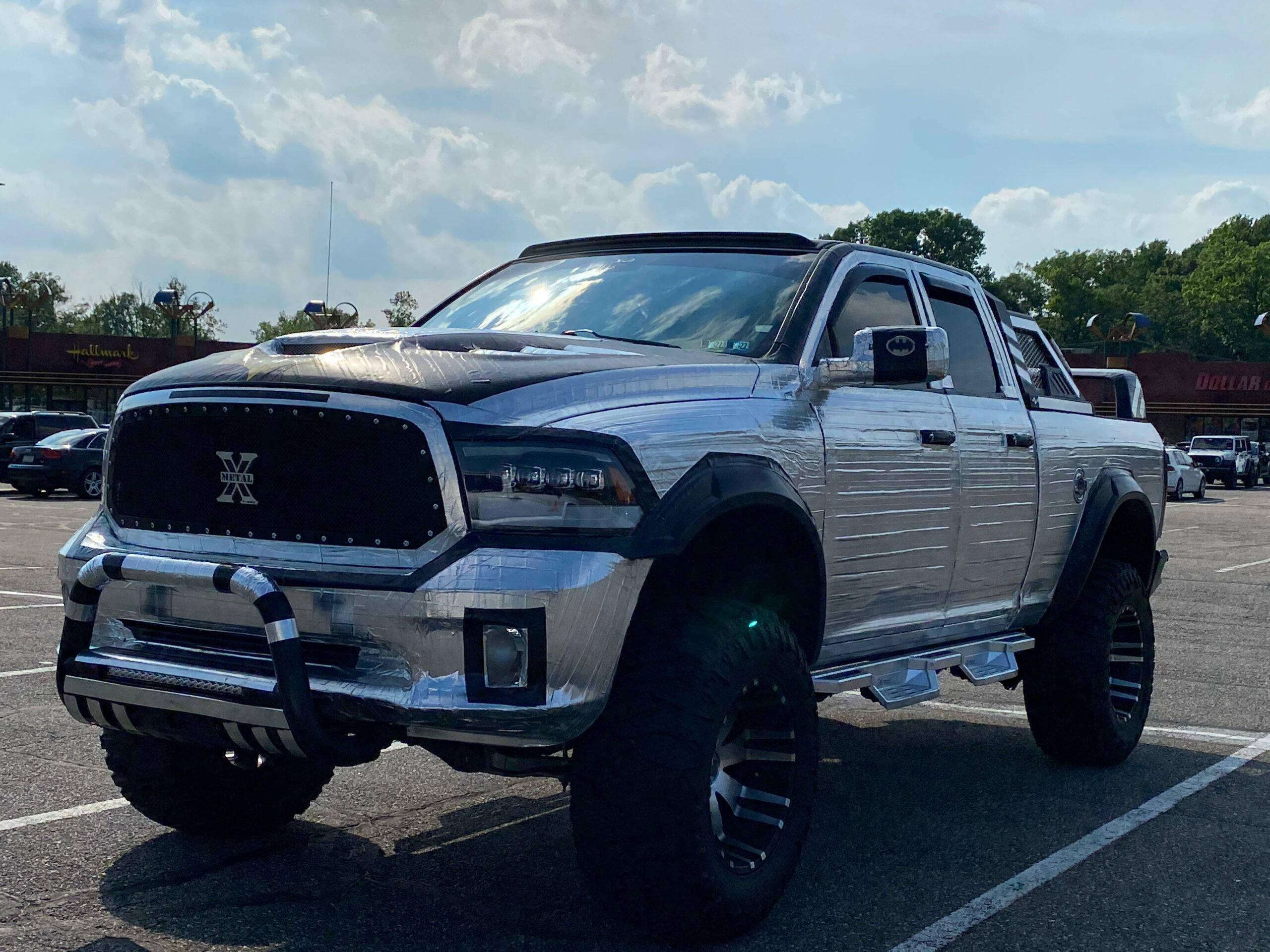 Pickup Truck 桌布 壁紙 — 一輛鍍鉻的Ram pickup truck，配備超大輪胎和定制格柵，停在陽光普照的停車場。