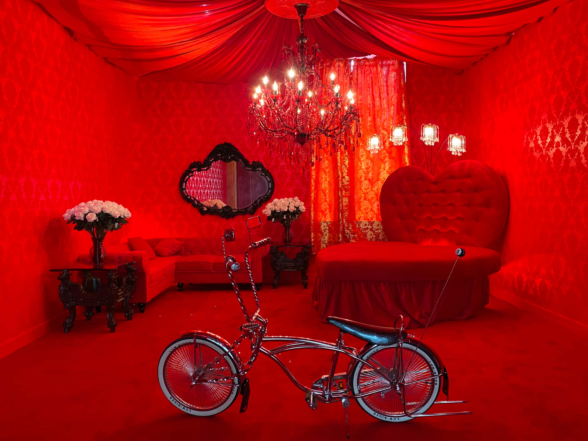 Red Room 桌布 壁紙 — 一輛鍍鉻腳踏車位於一個裝飾華麗、全紅色的臥室中央，配有心形床和吊燈。