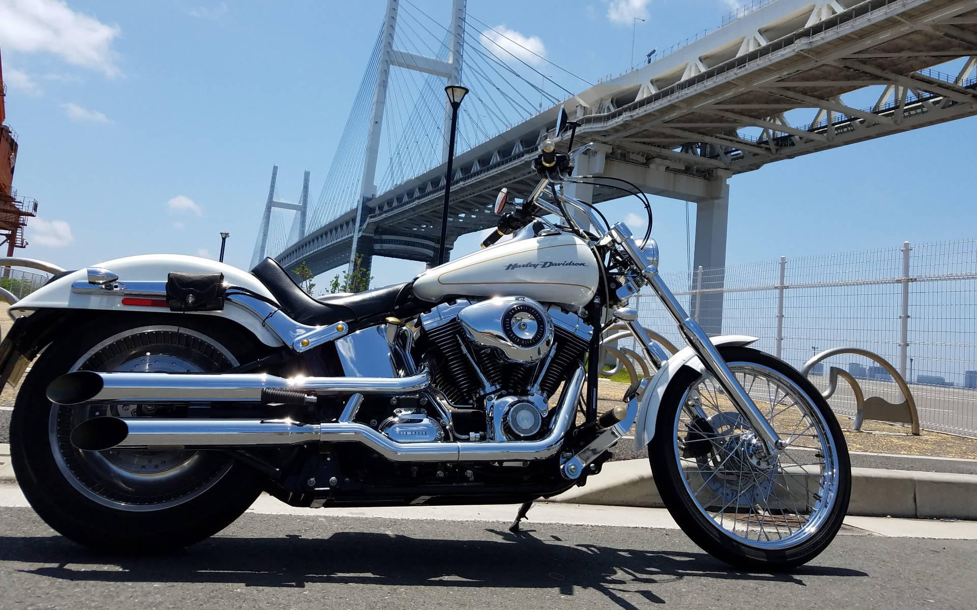 Yokohama 桌布 壁紙 — 一輛閃亮的白色Harley-Davidson機車停放在現代斜張橋下，陽光普照。
