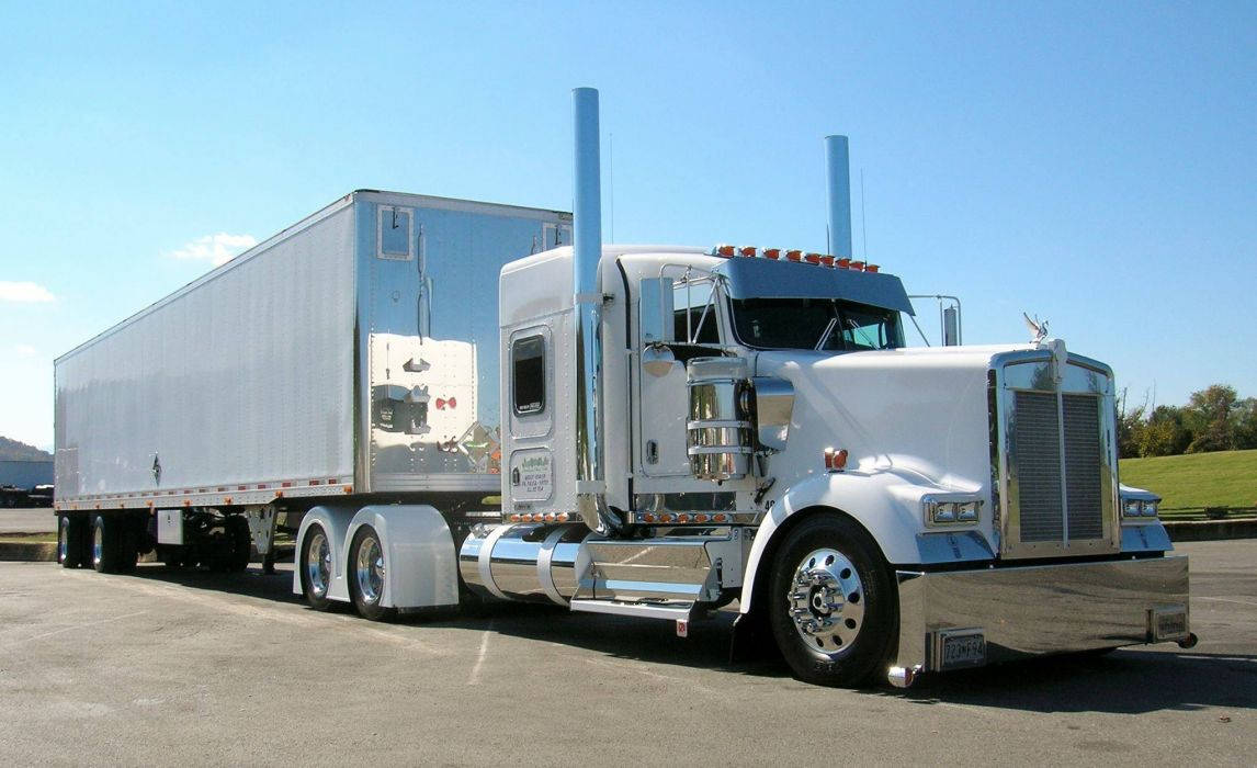 Kenworth 桌布 壁紙 — 一輛閃亮的白色半掛卡車，帶有鍍鉻裝飾和銀色拖車，停在晴朗藍天下的瀝青路面上。