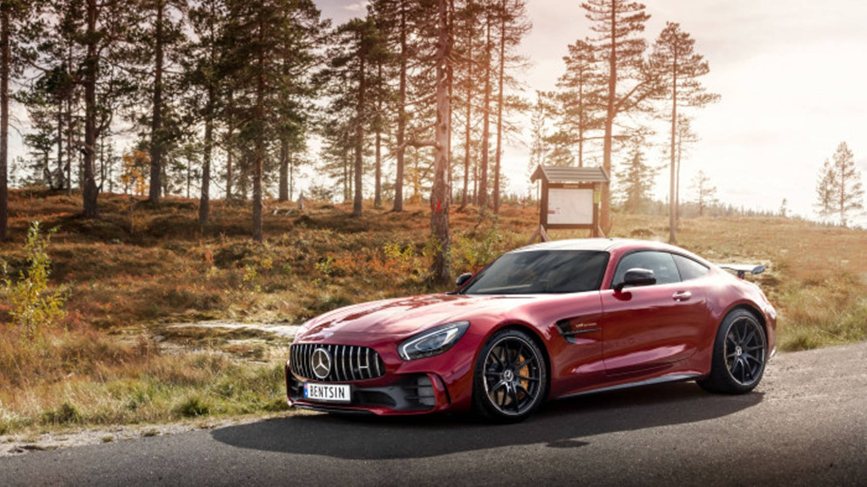 Mercedes 桌布 壁紙 — 一輛閃亮的紅色 Mercedes-AMG GT R 跑車停泊在沐浴著金色日落光線的森林道路上。