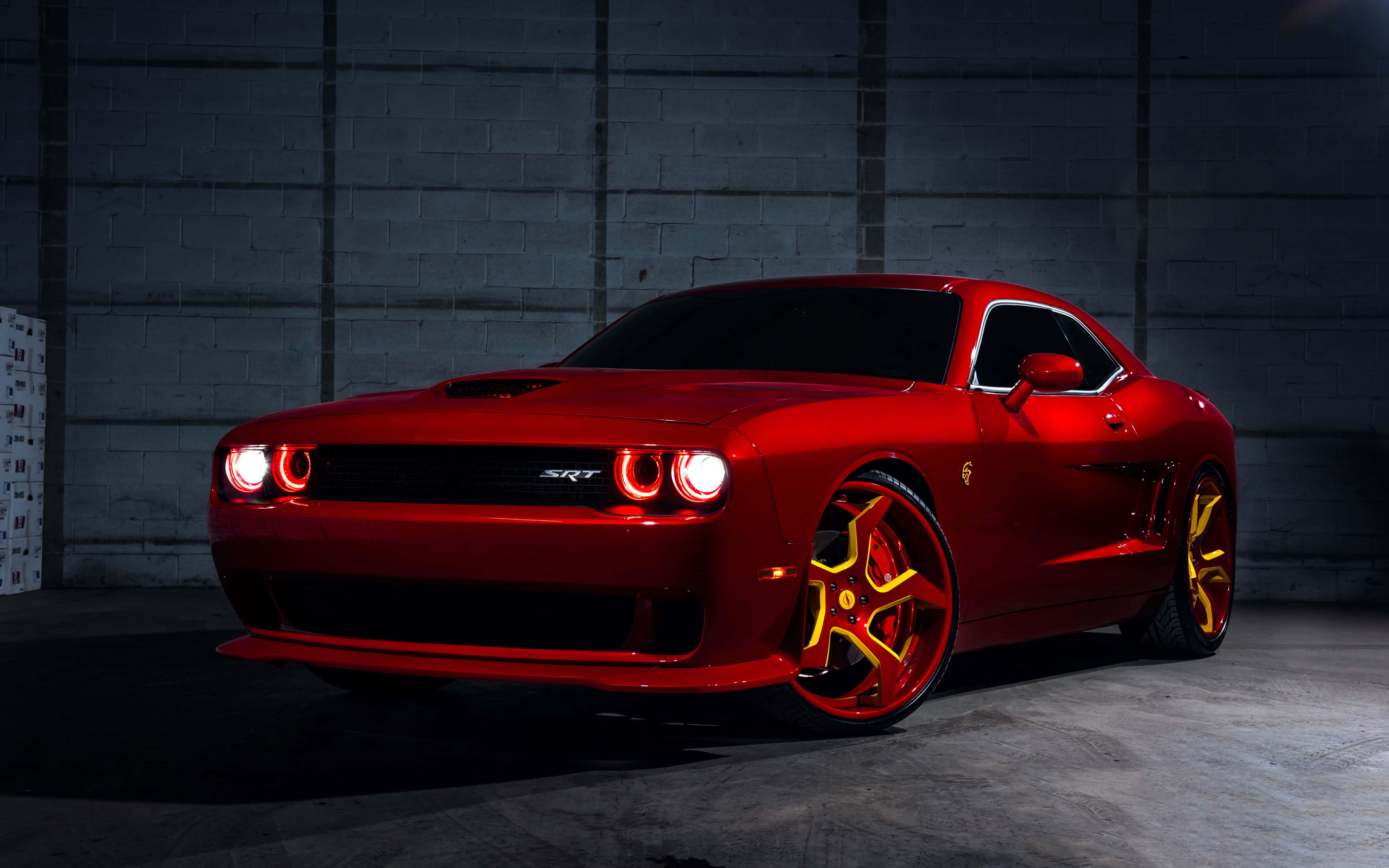 桌布 壁紙 — 一輛閃亮的紅色Dodge Challenger SRT配金色輪圈，在戲劇性燈光下於深色混凝土牆前閃耀。