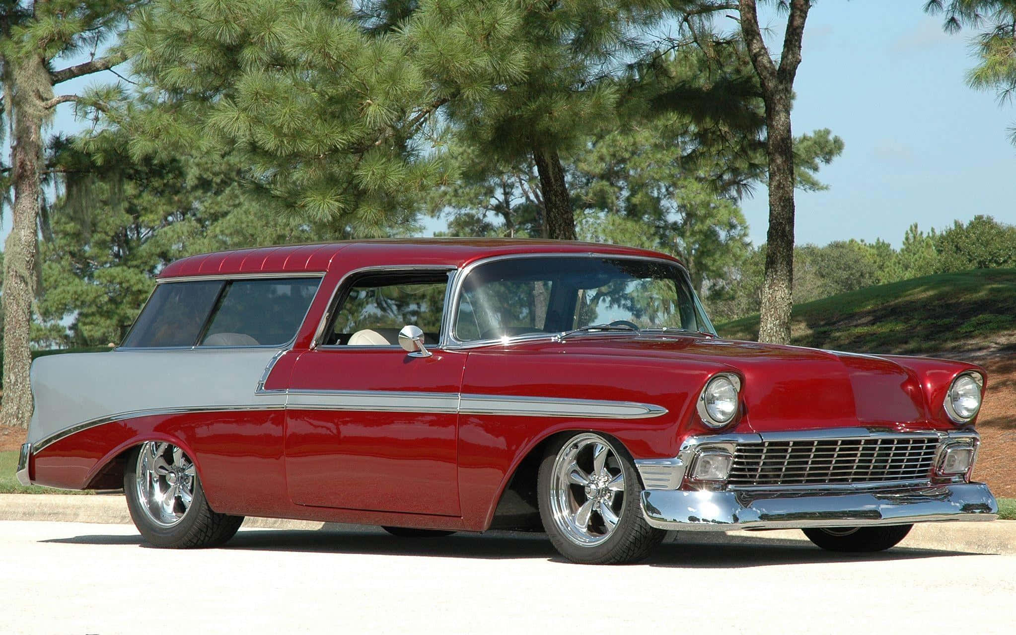 Chevrolet 桌布 壁紙 — 一輛閃亮的紅色和銀色1950年代雪佛蘭旅行車停在陽光明媚的日子裡，高大的松樹下的柏油路上。