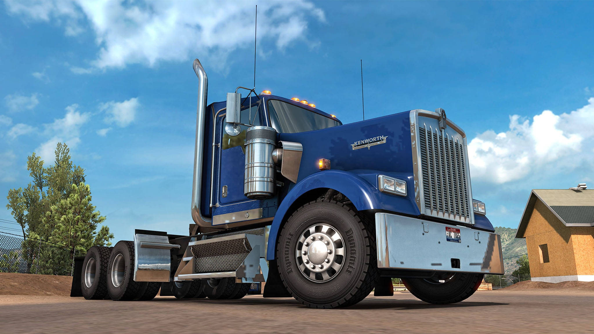 Kenworth W900 桌布 壁紙 — 一輛閃亮的藍色 Kenworth 半掛卡車停在泥土上，天空湛藍，白雲朵朵。