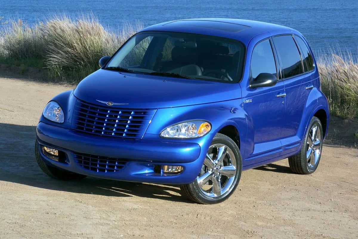 Chrysler Pt Cruiser 桌布 壁紙 — 一輛閃亮的藍色PT Cruiser停泊在沙灘上，背景是海洋和沙丘草。