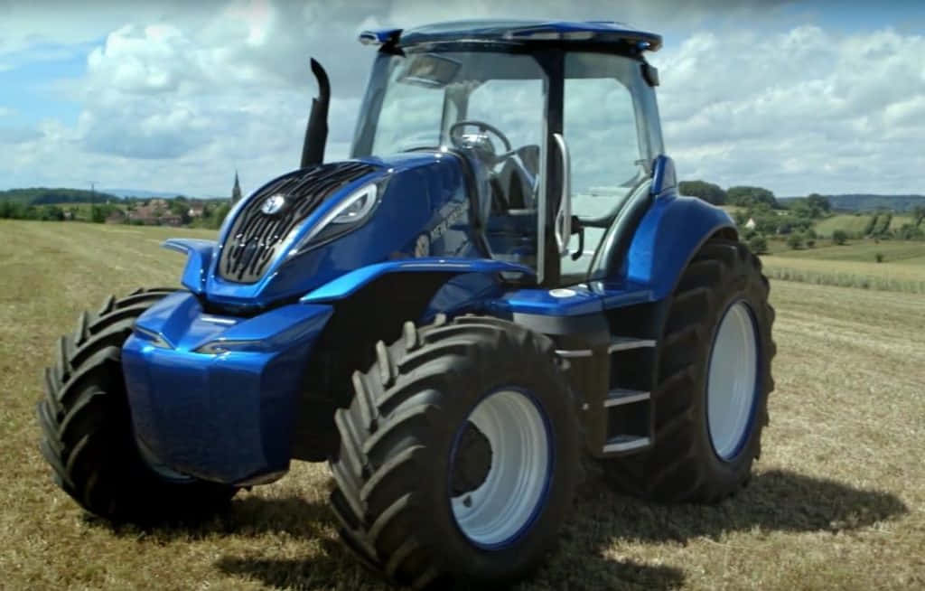Tractor 桌布 壁紙 — 一輛閃亮的藍色現代拖拉機在部分多雲的天空下，突出地矗立在乾燥的草地上。