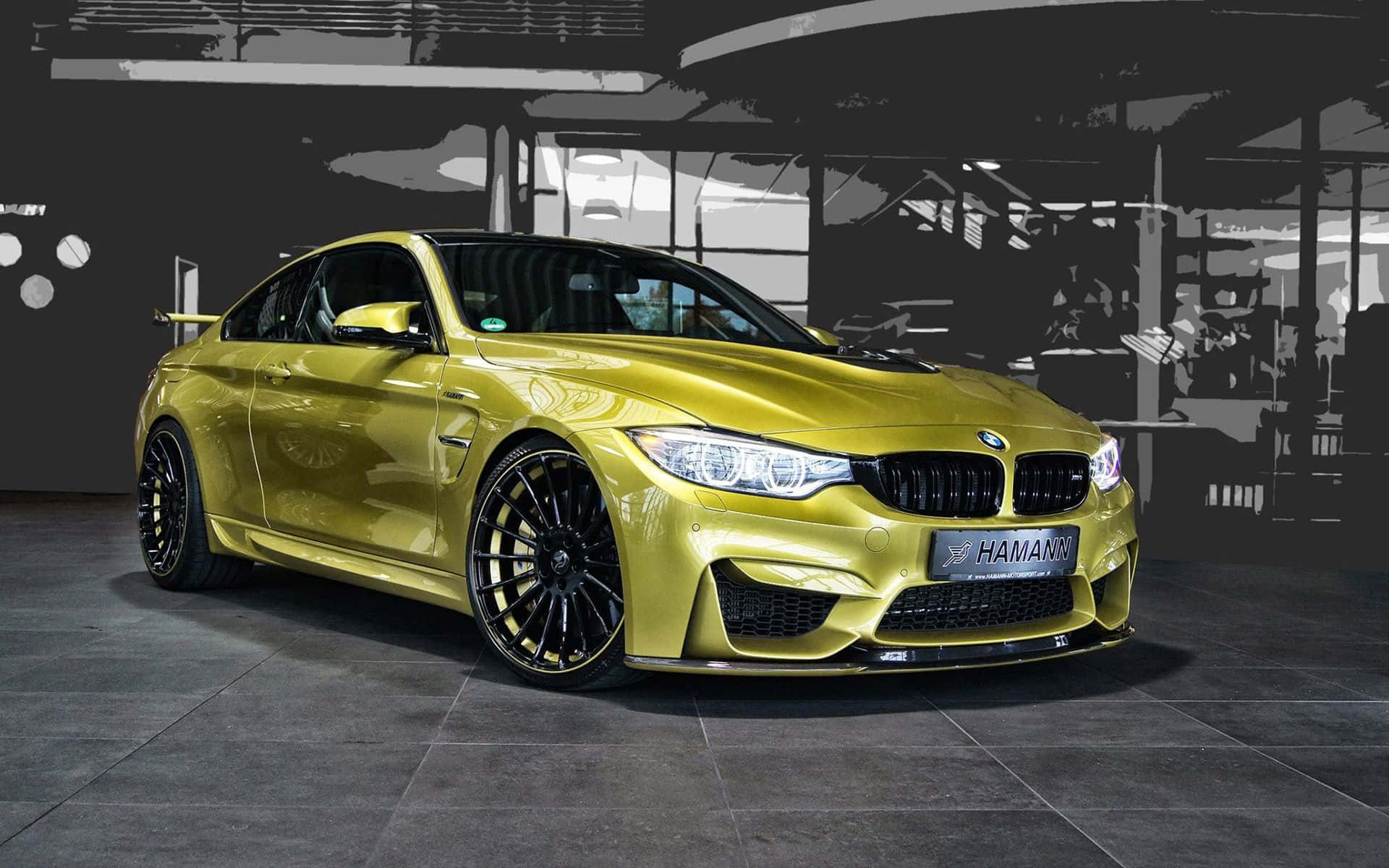 BMW 動圖 桌布 壁紙 — 一輛閃亮的金色BMW M4配備黑色輪圈和Hamann調校，停在單色工業車庫中。