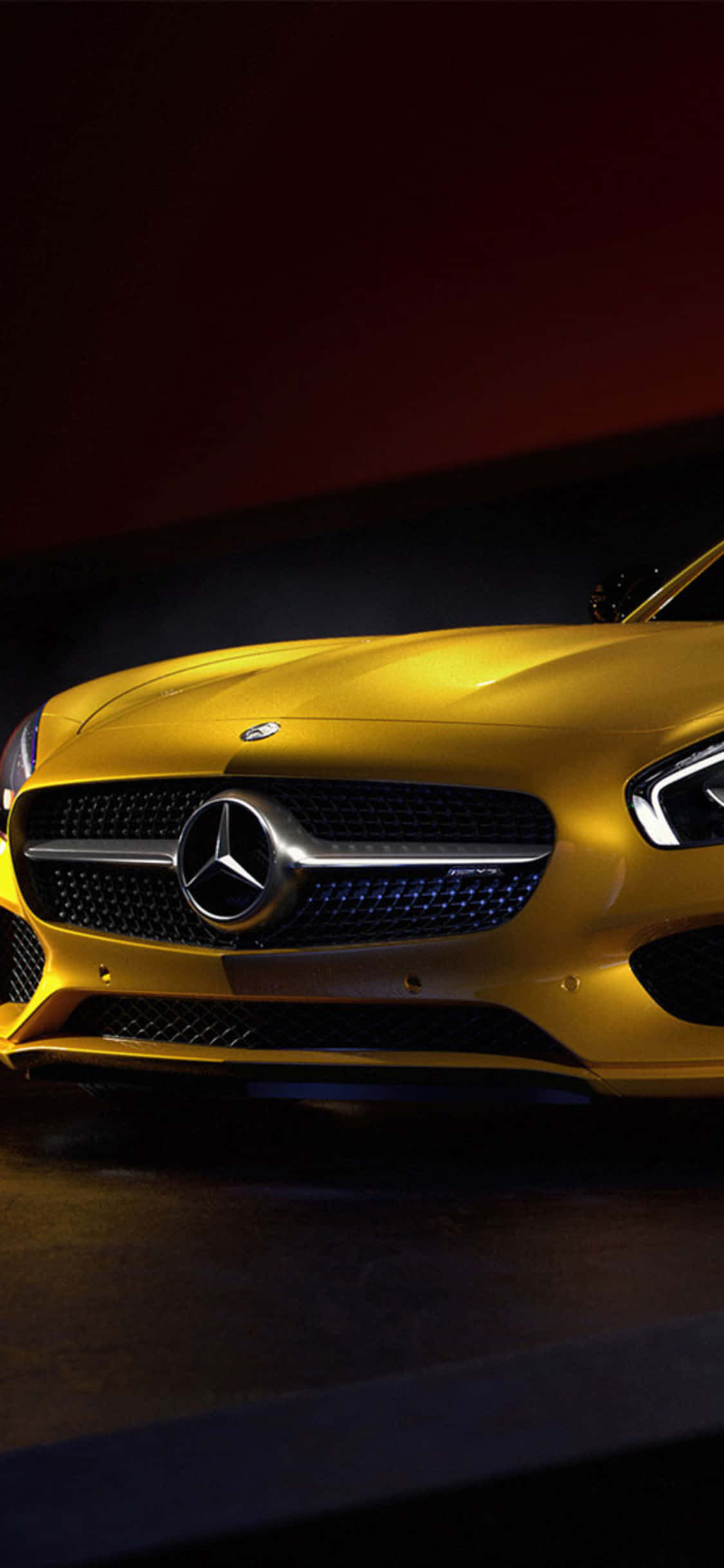 iPhone X Amg Gt-r 桌布 壁紙 — 一輛閃亮的金色梅賽德斯跑車在深紅色和黑色背景下從下方戲劇性地照亮。