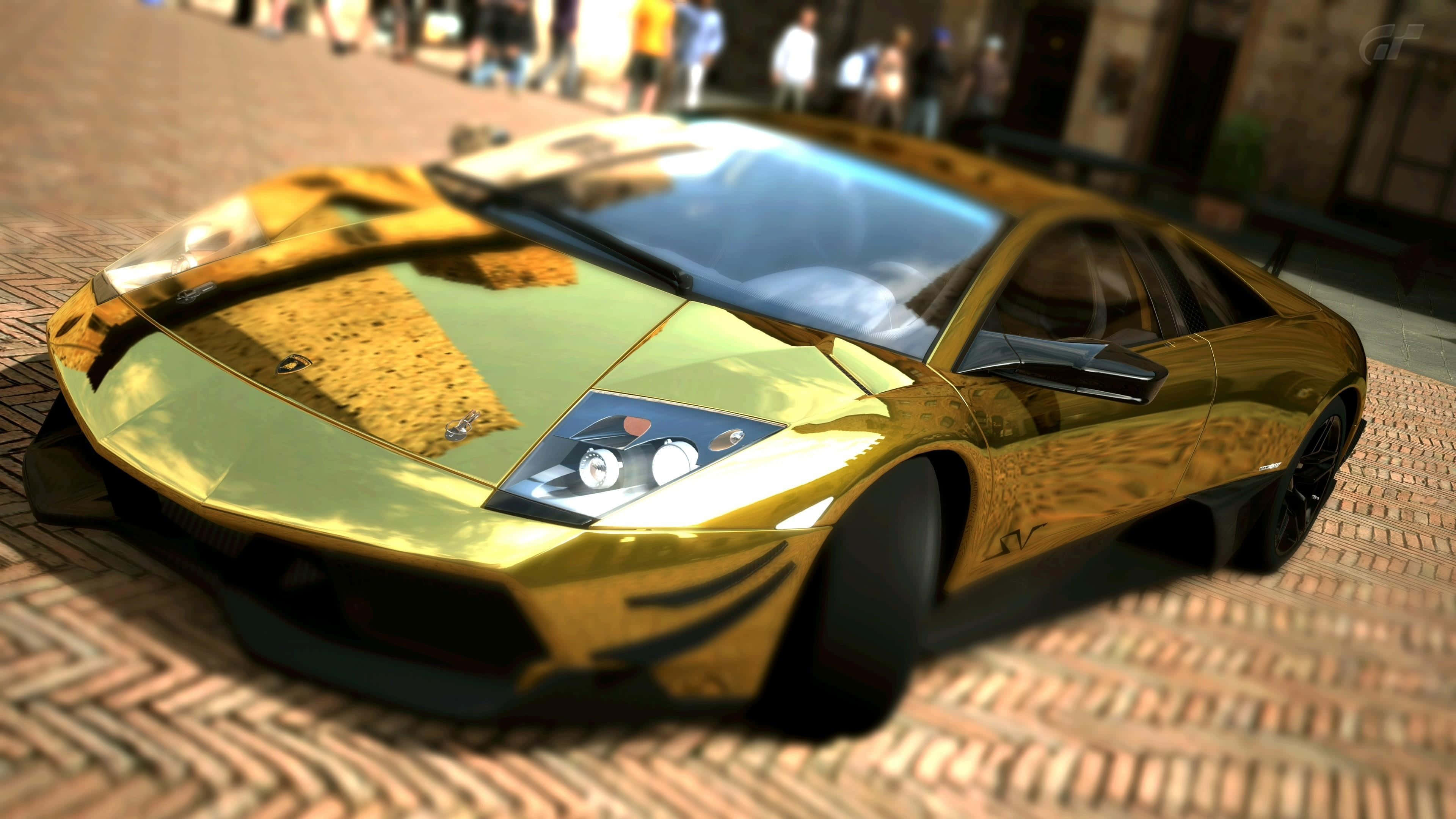 Gold Cars 桌布 壁紙 — 一輛閃亮的金色藍寶堅尼跑車停泊在鵝卵石街道上，背景有模糊的行人。