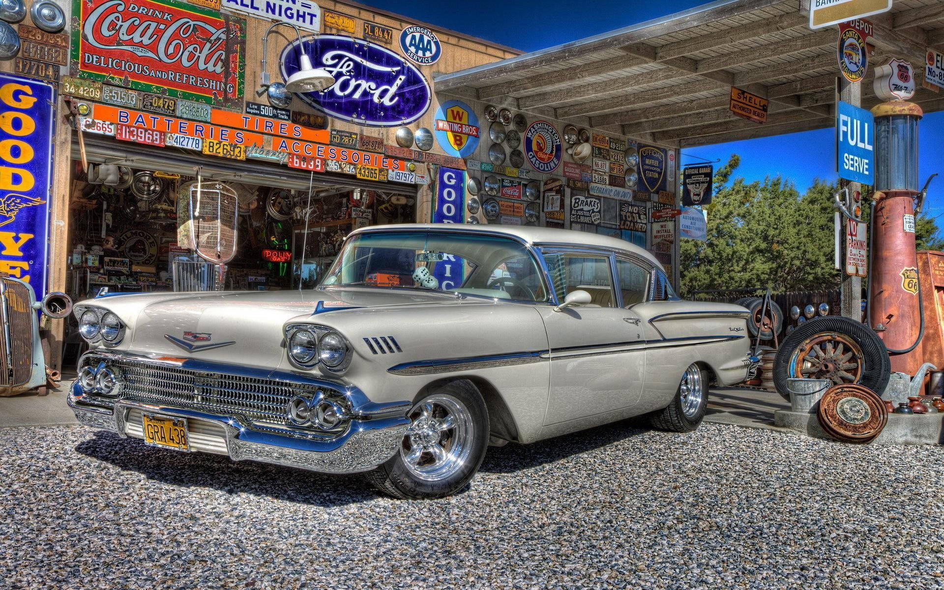 Gas Station 桌布 壁紙 — 一輛閃亮的銀色1957年雪佛蘭Bel Air停放在復古加油站，背景是明亮的藍天。