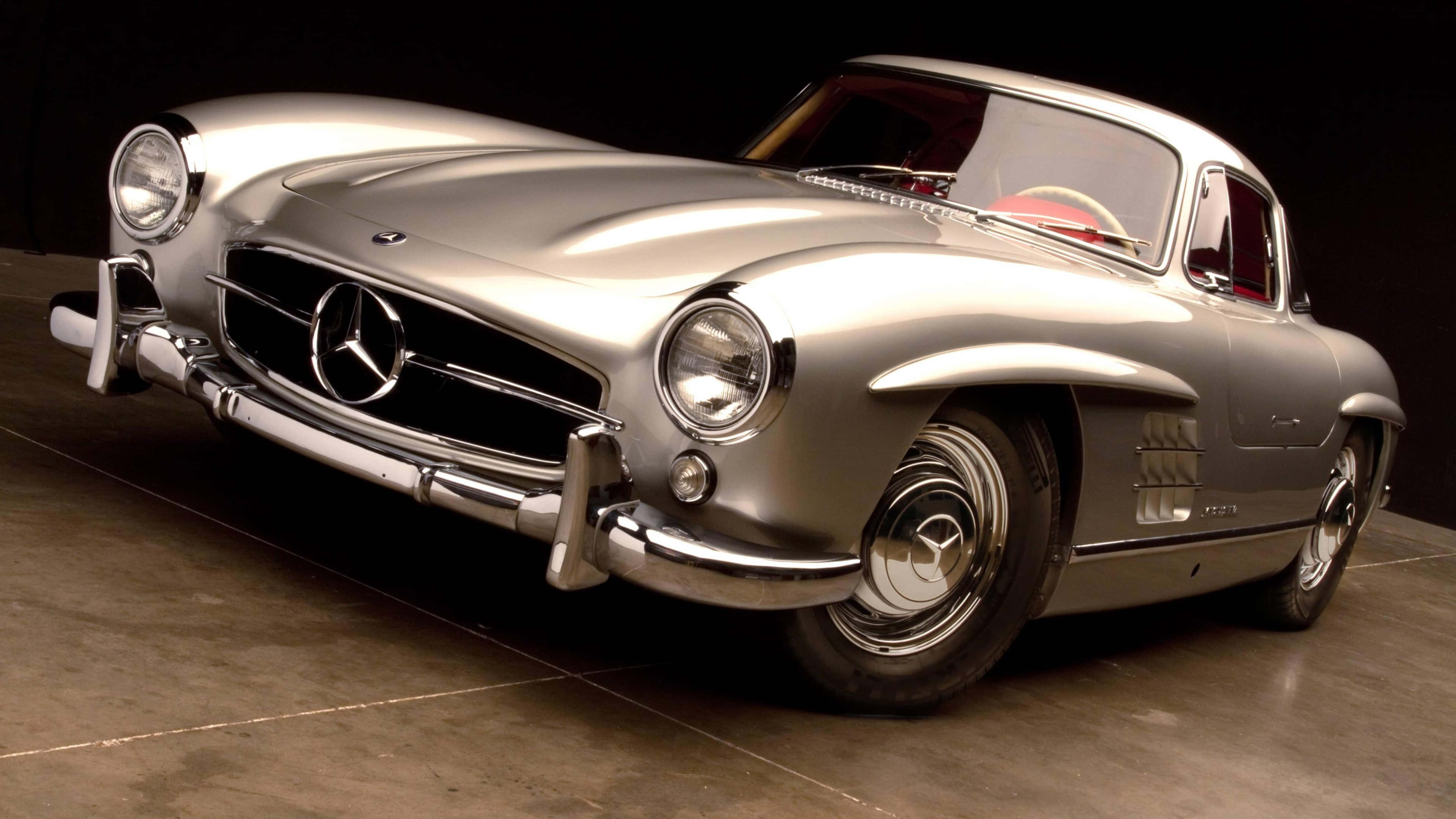 Classic Mercedes 桌布 壁紙 — 一輛閃亮的銀色賓士300SL鷗翼跑車，帶有鍍鉻裝飾和紅色內裝，在攝影棚中以戲劇性燈光拍攝。