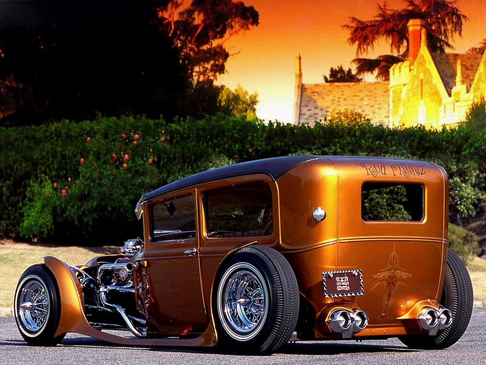 經典汽車 桌布 壁紙 — 一輛閃亮的青銅色hot rod，帶有鍍鉻細節，停在夕陽下的瀝青路上，背景是石屋和綠色籬笆。