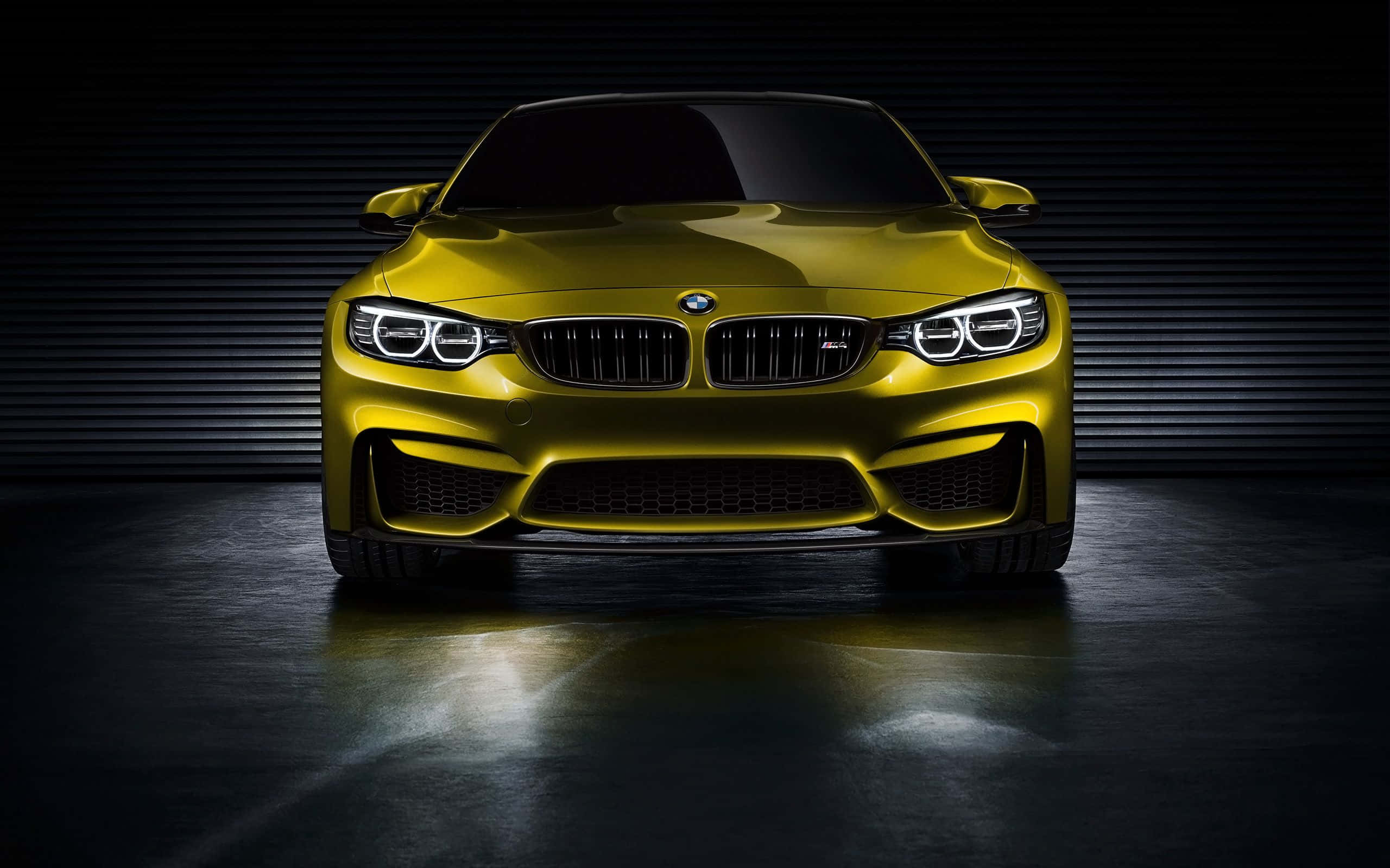 BMW 動圖 桌布 壁紙 — 一輛閃亮的黃色BMW M4跑車在攝影棚內，從下方戲劇性地照亮，背景為深色波紋板。