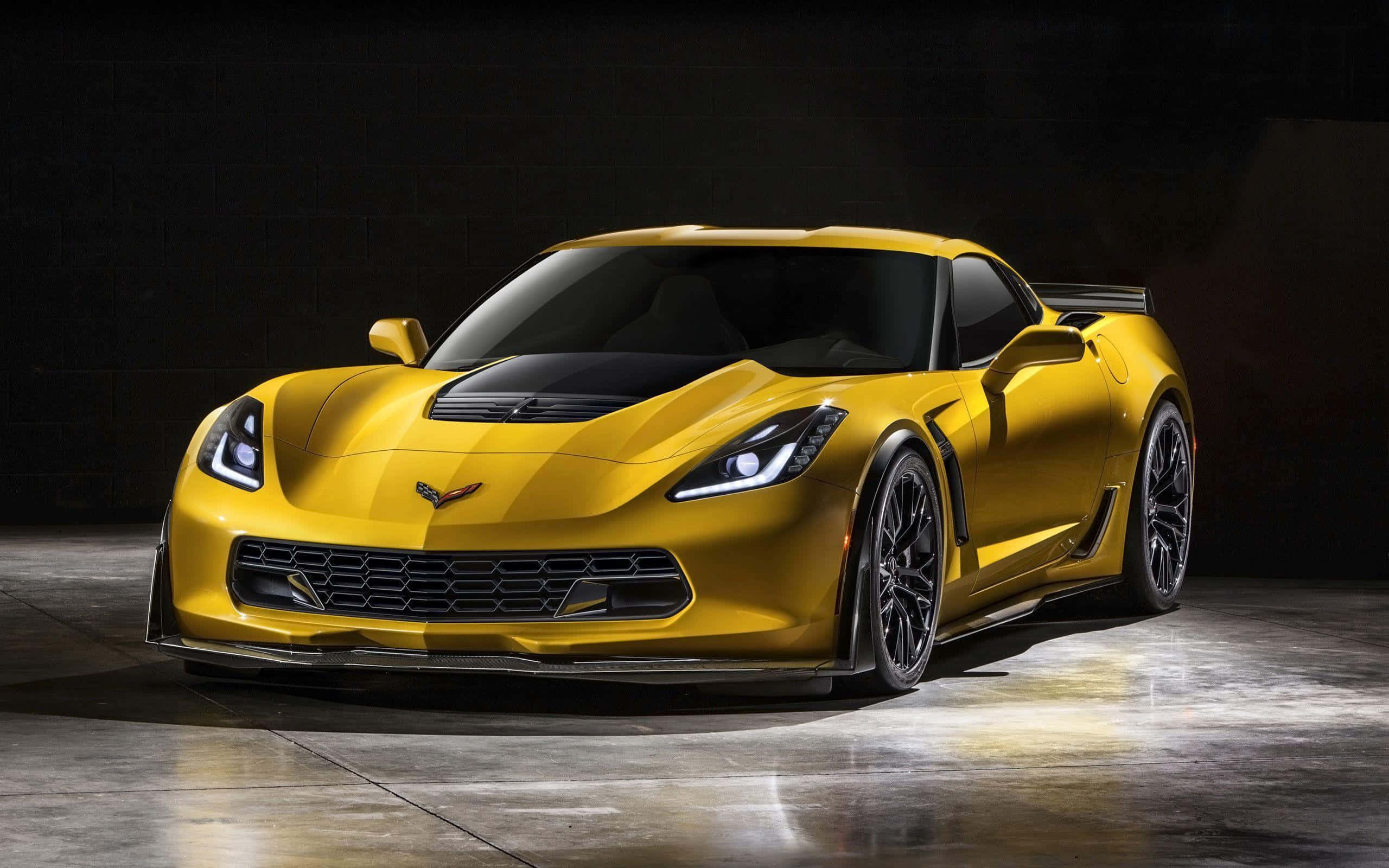 Chevrolet Corvette Z06 桌布 壁紙 — 一輛閃亮的黃色雪佛蘭克爾維特跑車在黑暗的攝影棚背景下，搭配反射性混凝土地板，被戲劇性地照亮。