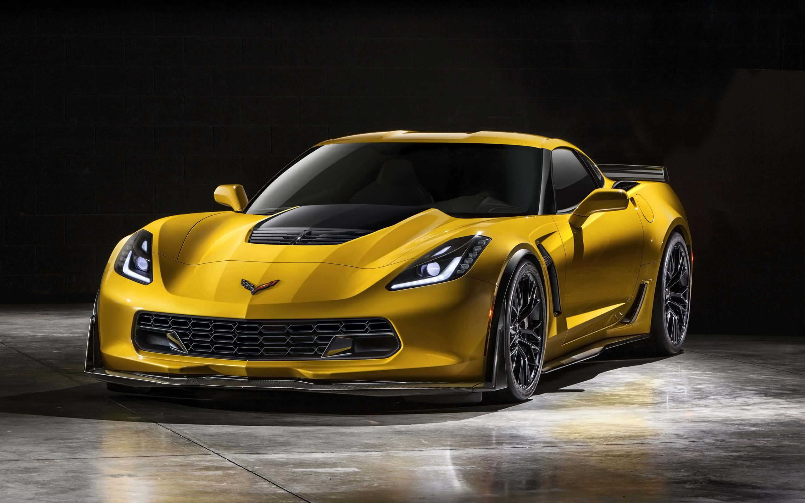 corvette 桌布 壁紙 — 一輛閃亮的黃色雪佛蘭克爾維特跑車在黑暗的攝影棚中，被戲劇性地照亮，地板是反射性混凝土。